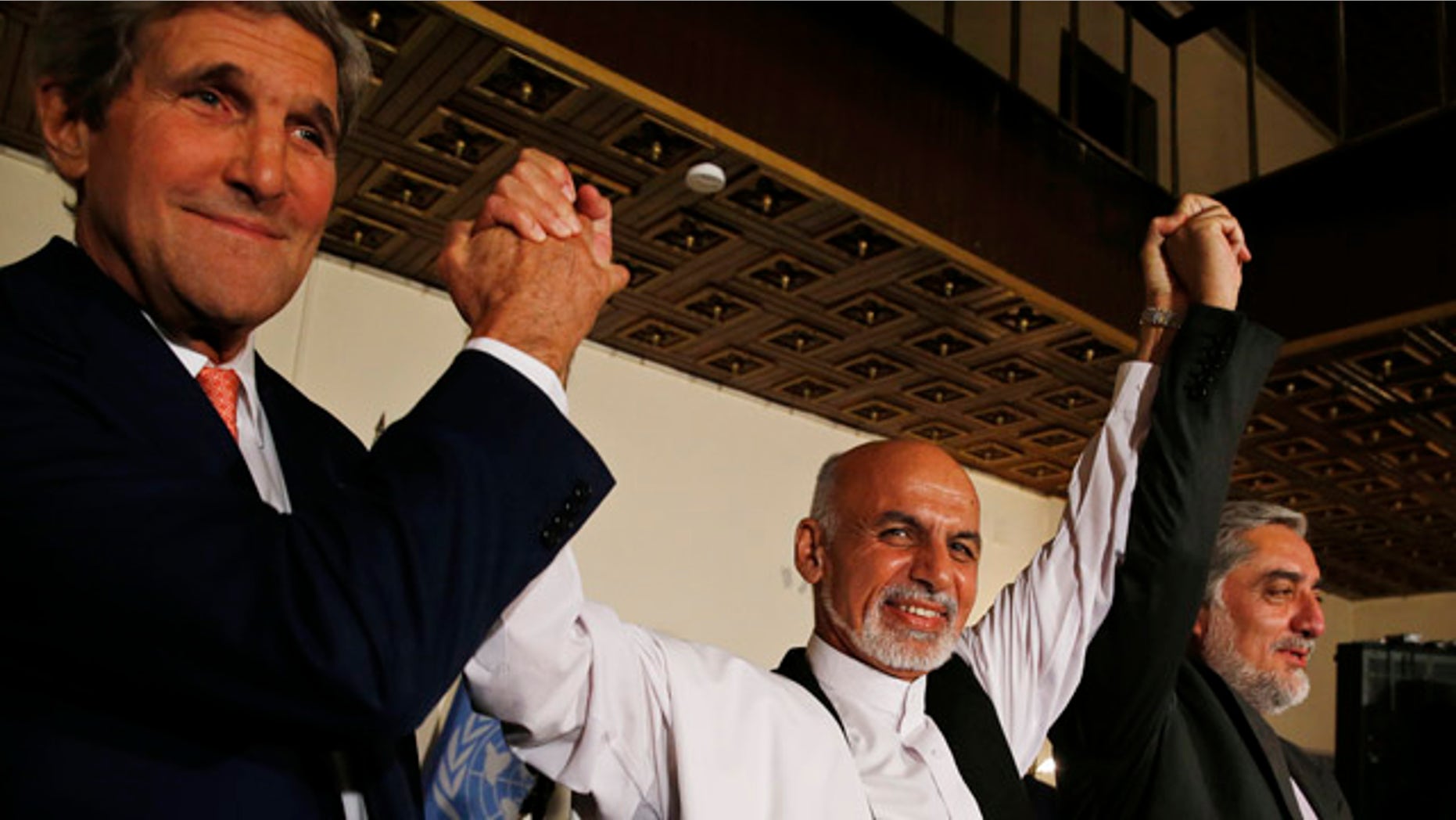 July 12, 2014: U.S. Secretary of State John Kerry, left, and Afghanistan's presidential candidates Ashraf Ghani, center, and Abdulah Abdullah hold their arms in the air together after announcing a deal for the auditing of all Afghan election votes at the United Nations Compound in Kabul. (AP Photo/Jim Bourg, Pool)