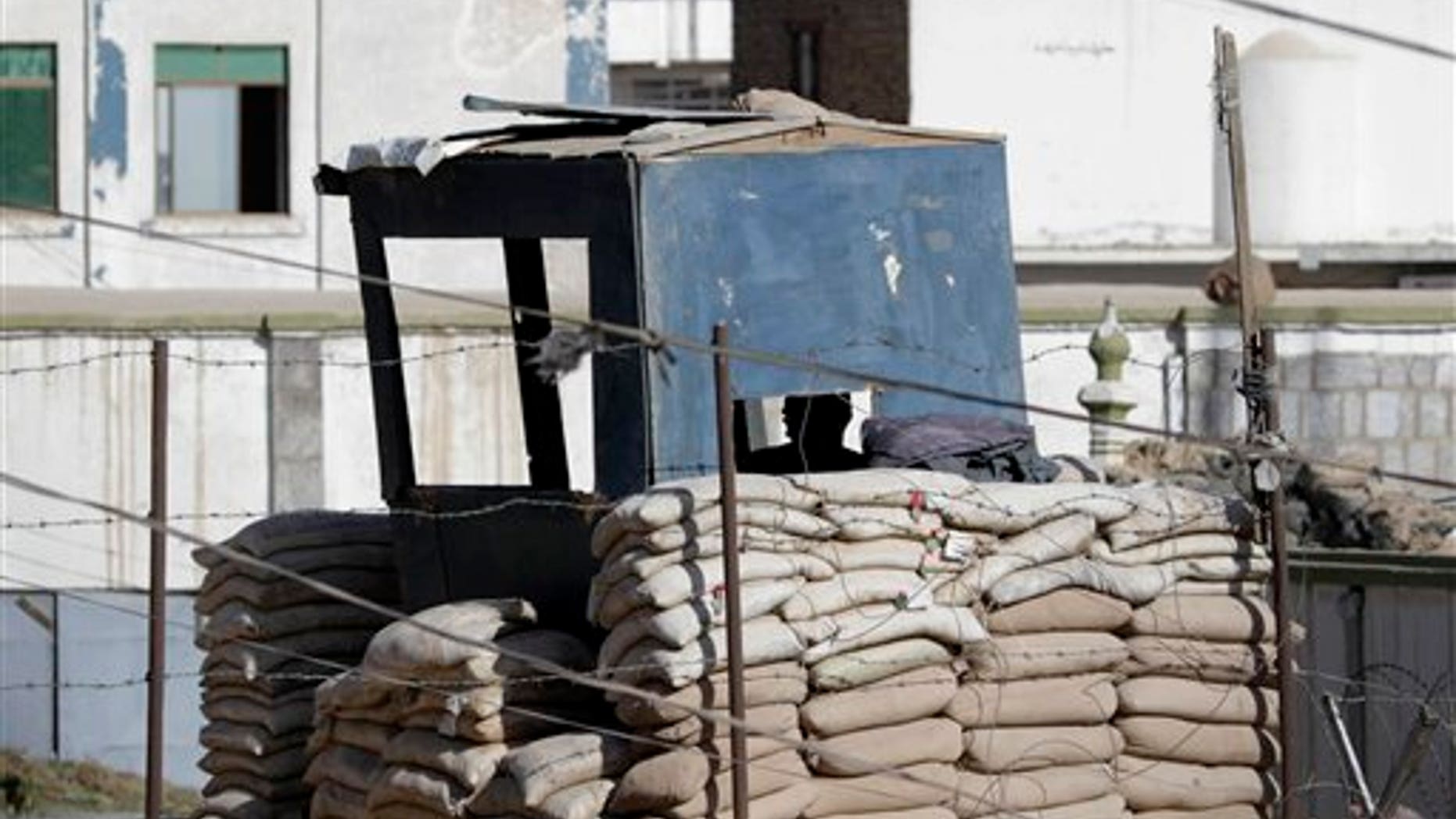 May 7: An Afghan security officer looks out from his sheltered vantage point on a rooftop after gunmen launched an attack on the compound of the governor of Kandahar province in Kandahar, south of Kabul, Afghanistan. (AP)