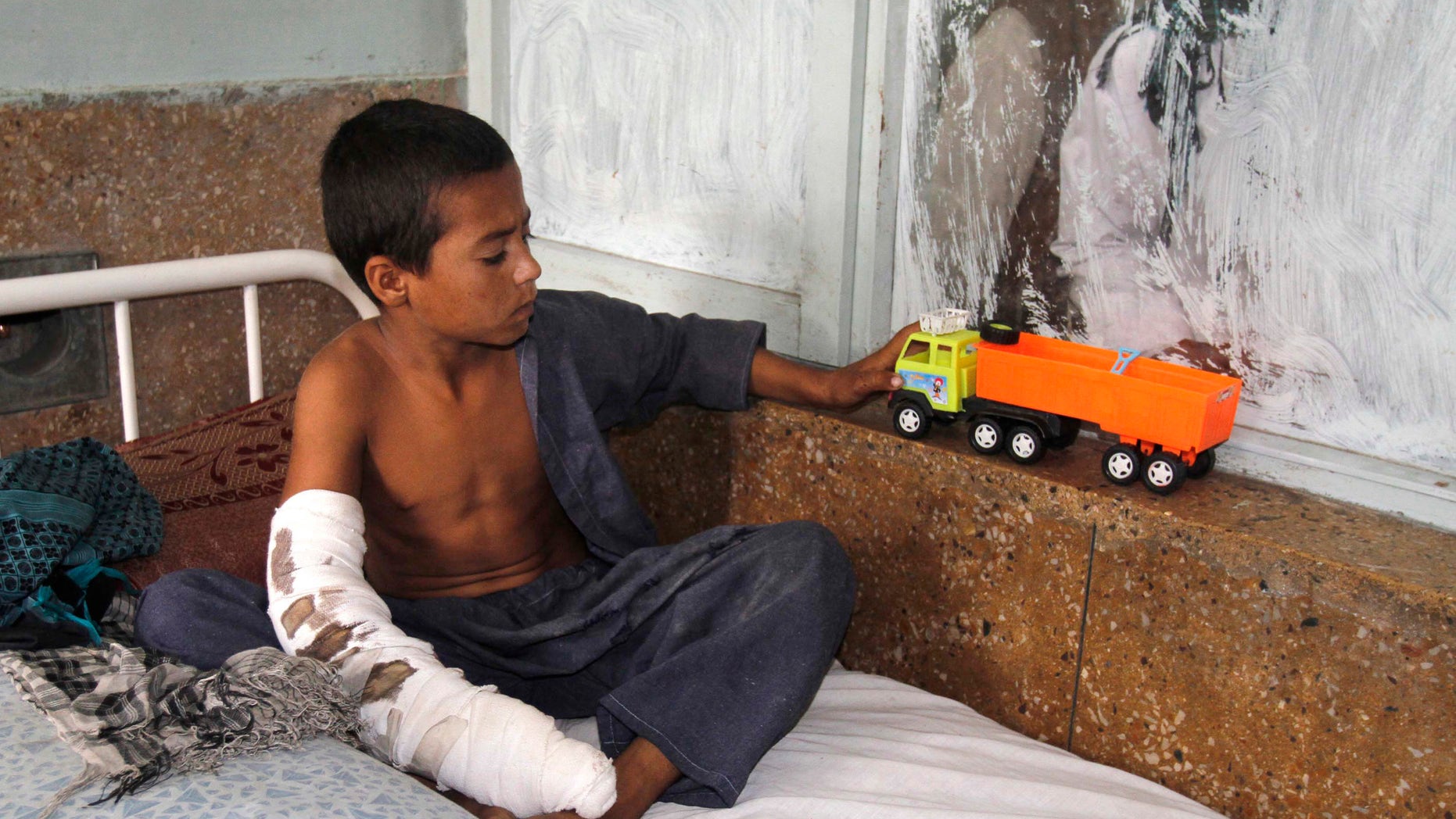 An Afghan boy plays with his toy at a hospital after he was injured by insurgent rocket fire near to the air base of Jalalabad, Afghanistan, Tuesday, Oct. 4, 2011. Two women and three children were injured by the rocket attack, governor spokesman said.