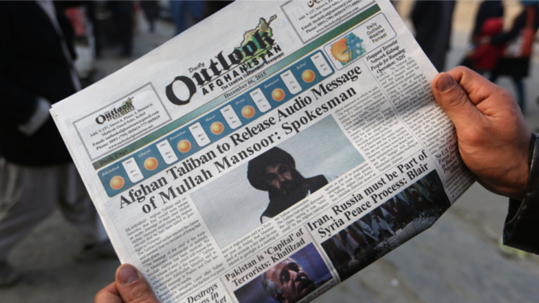 An Afghan man reads a local newspaper with photos of the new leader of the Afghan Taliban, Mullah Akhtar Mansoor.