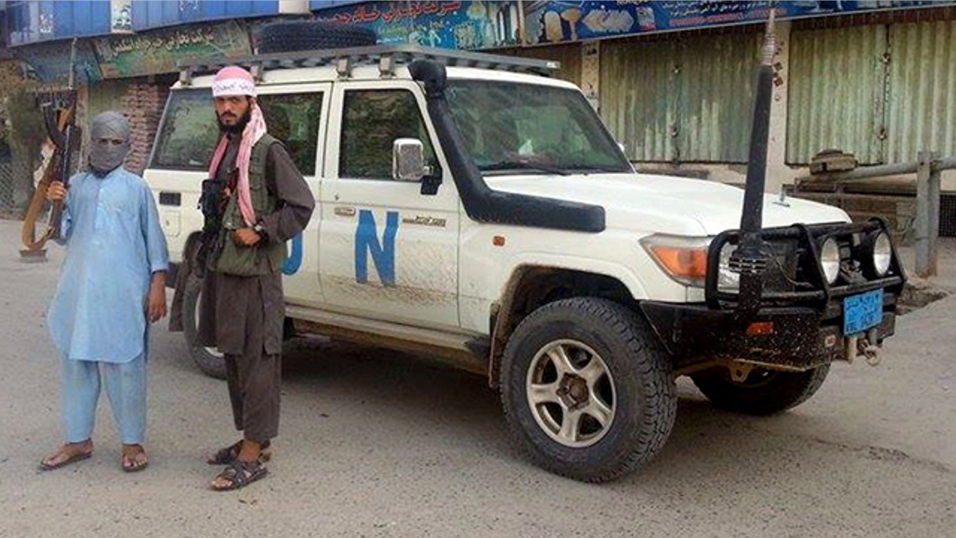FILE - In this Sept. 29, 2015 file photo, Taliban fighters pose for a photo next to a UN vehicle they plundered in Kunduz, Afghanistan. (AP Photo/File)