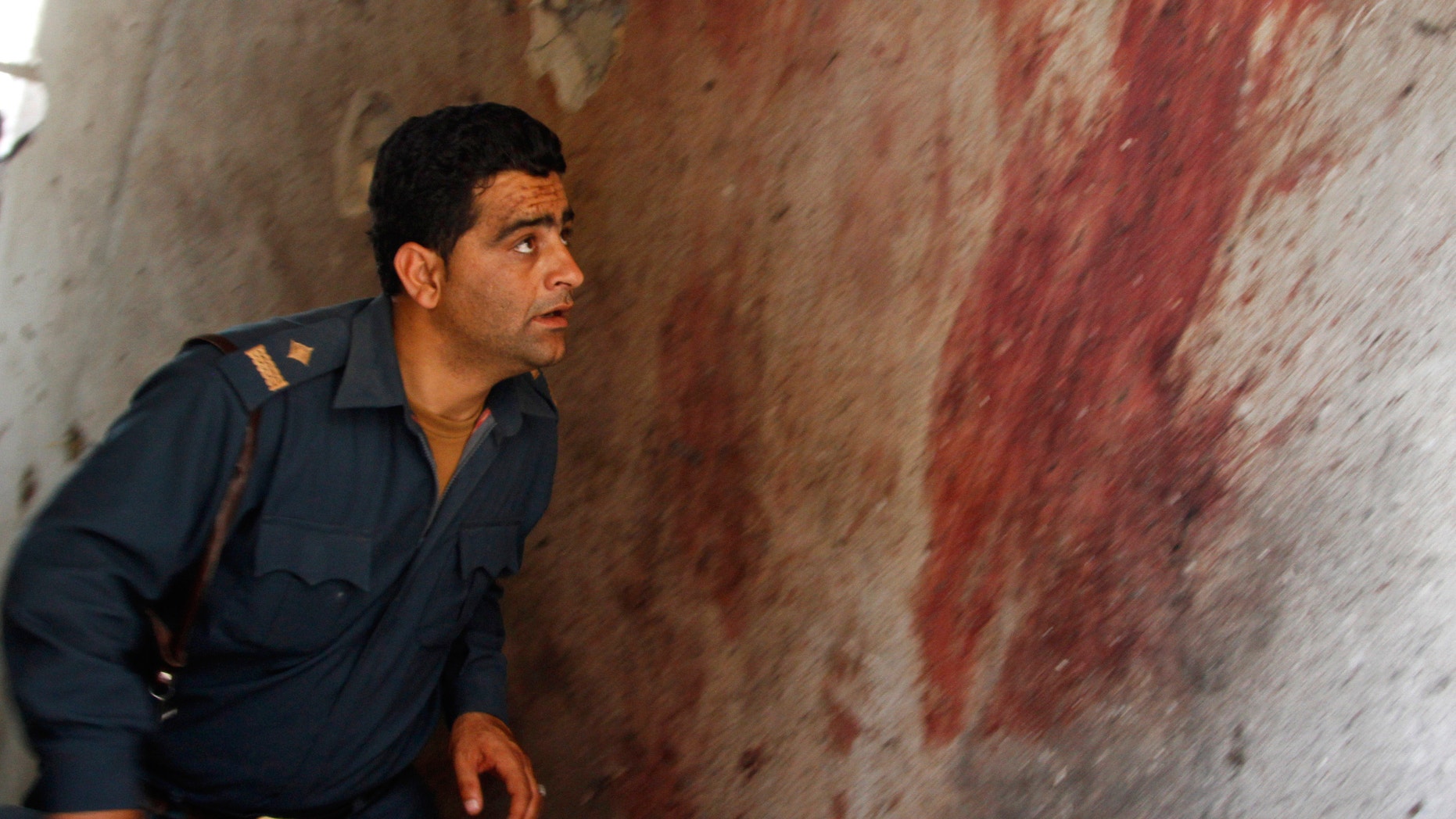 June, 10, 2013 - An Afghan policeman investigates the site after Taliban fighters attacked near Kabul airport, Afghanistan.
