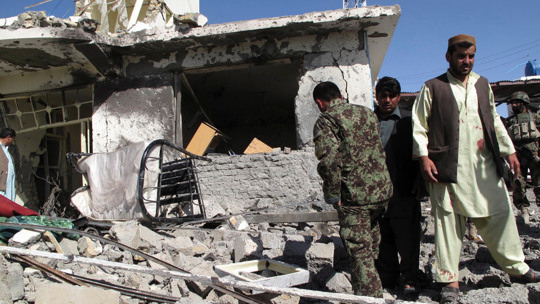 Afghans gather at the site of a bombing in Lashkar Gah, Helmand province, south of Kabul, Afghanistan, Monday, Oct. 8, 2012. A bomb hidden in a parked minibus exploded outside a government office in a southern Afghan city on Monday, killing two Afghan intelligence officers and wounding over a dozen other people, officials said. (AP Photo)