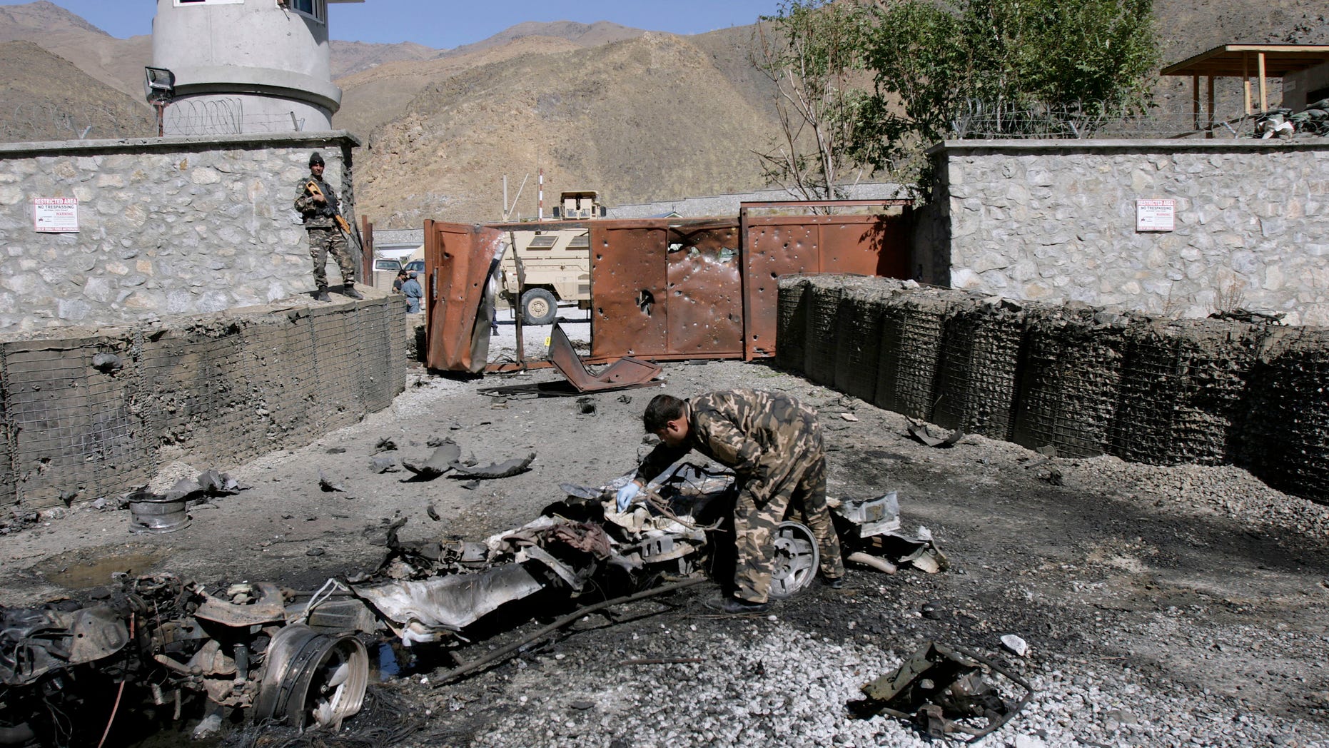 An Afghan security officer, center, collects evidence from the site of an attack by militants at the gate of an American base in Panjshir north of Kabul, Afghanistan, Saturday, Oct. 15, 2011.