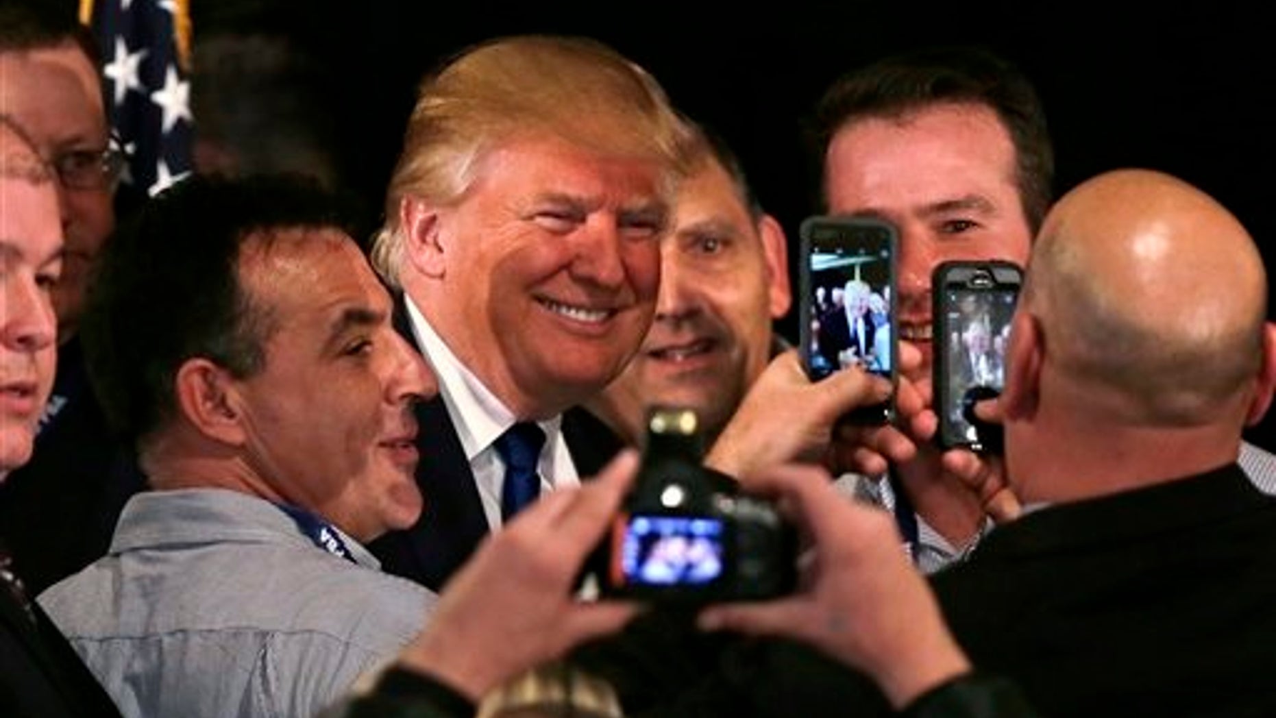 Republican presidential candidate, businessman Donald Trump smiles as he has his photograph taken with supporters after being endorsed at a regional police union meeting in Portsmouth, N.H., Thursday, Dec. 10, 2015. (AP Photo/Charles Krupa)