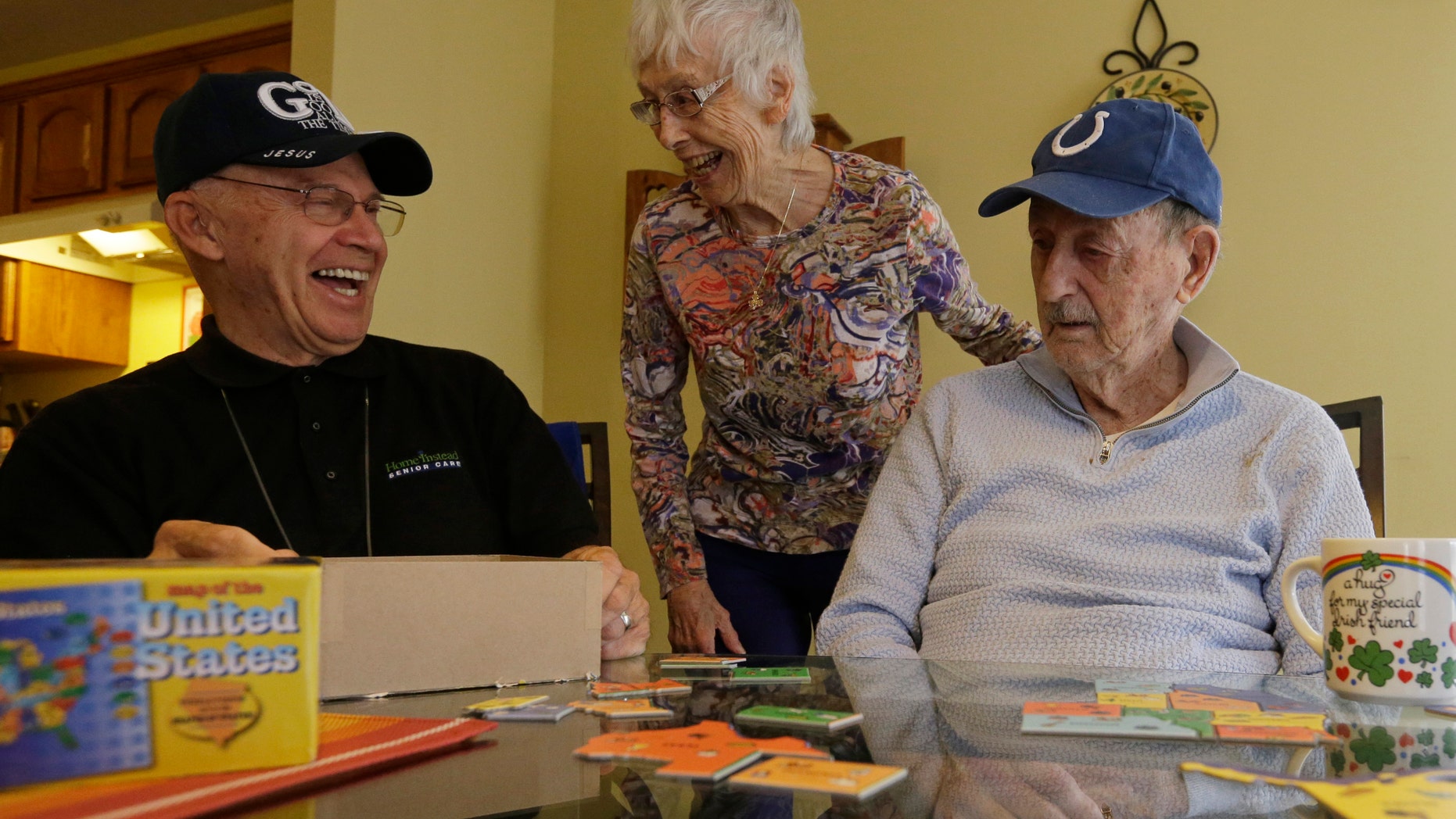 Caregiver Warren Manchess with Paul Gregoline and Paul's wife, Mary, as they work on a puzzle, in Noblesville, Ind.