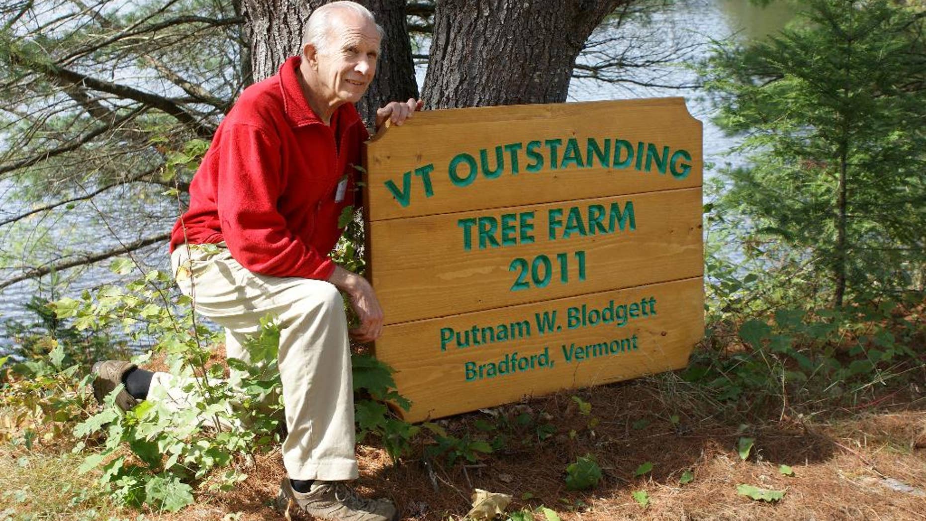 In this 2011 photo, Putnam “Put” Blodgett poses by a sign announcing he was named Vermont's 2011 Outstanding Tree Farmer in Bradford, Vt. Blodgett, president of the Vermont Woodlands Association, has implemented a succession plan for his 670 acres family owned forest land by forming a limited liability company and establishing a conservation easement on the land that prohibits development and mandates professional forest management. (AP Photo/Vermont Woodlands Association)
