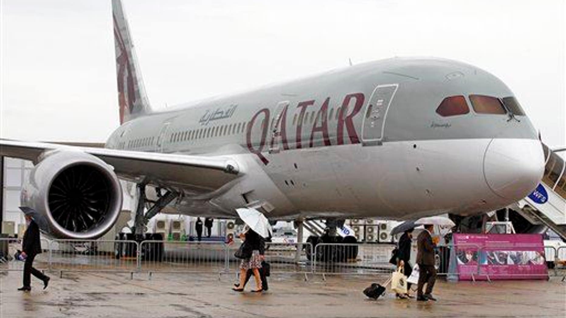 Visitors walk past a Qatar Airways Boeing Dreamliner, displayed at the 50th Paris Air Show at Paris-Le Bourget Airport, north of Paris, June 20, 2013.
