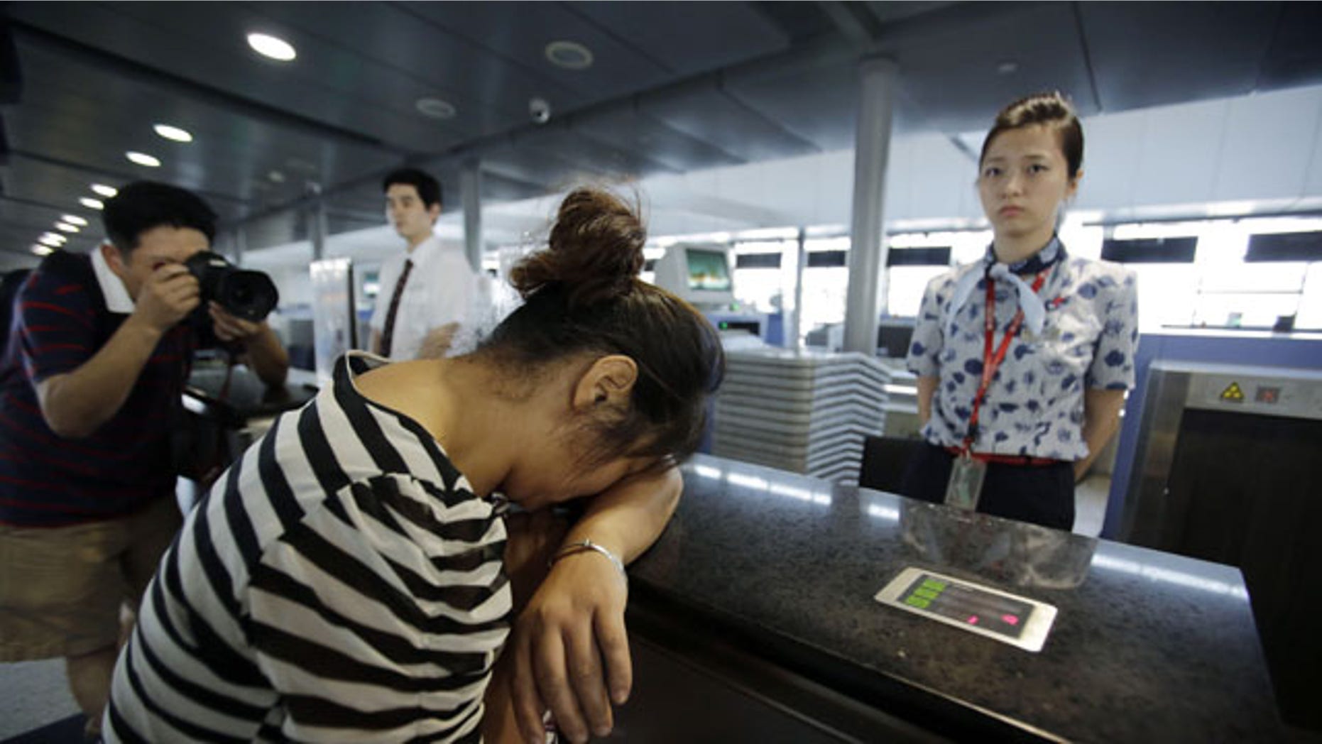 FILE - In this July 8, 2013 file photo, an unidentified family member of one of two Chinese students killed in a crash of an Asiana Airlines' plane on Saturday, cries at the airline's counter as she and other family members check in for a flight to San Francisco, at Pudong International Airport in Shanghai, China.
