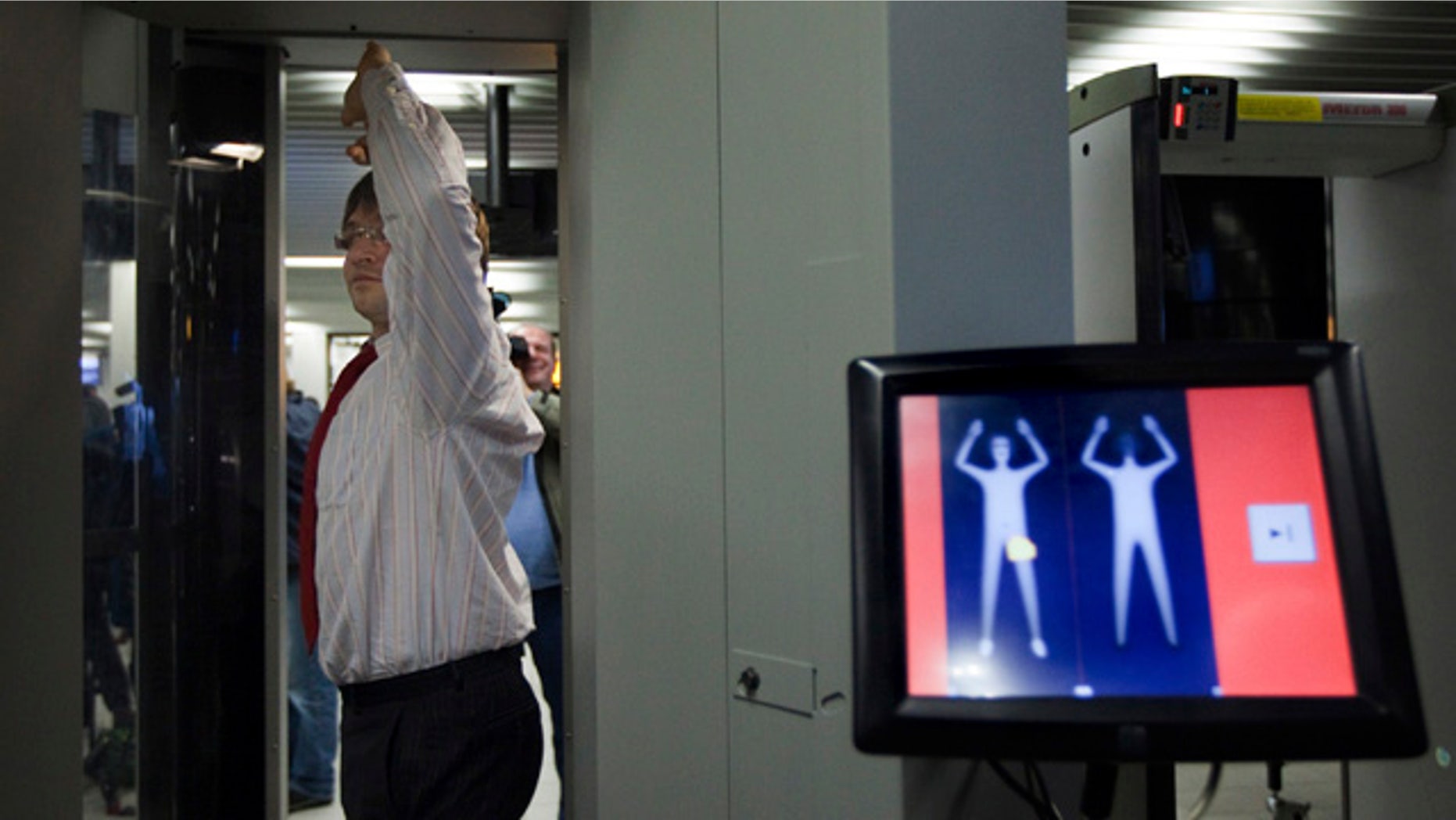An employee of Schiphol stands inside a body scanner during a demonstration at a press briefing at Schiphol airport, Netherlands. The Netherlands announced Wednesday, Dec. 30, it will immediately begin using full body scanners for flights heading to the United States, issuing a report that called the failed Christmas Day airline bombing a "professional" terror attack.