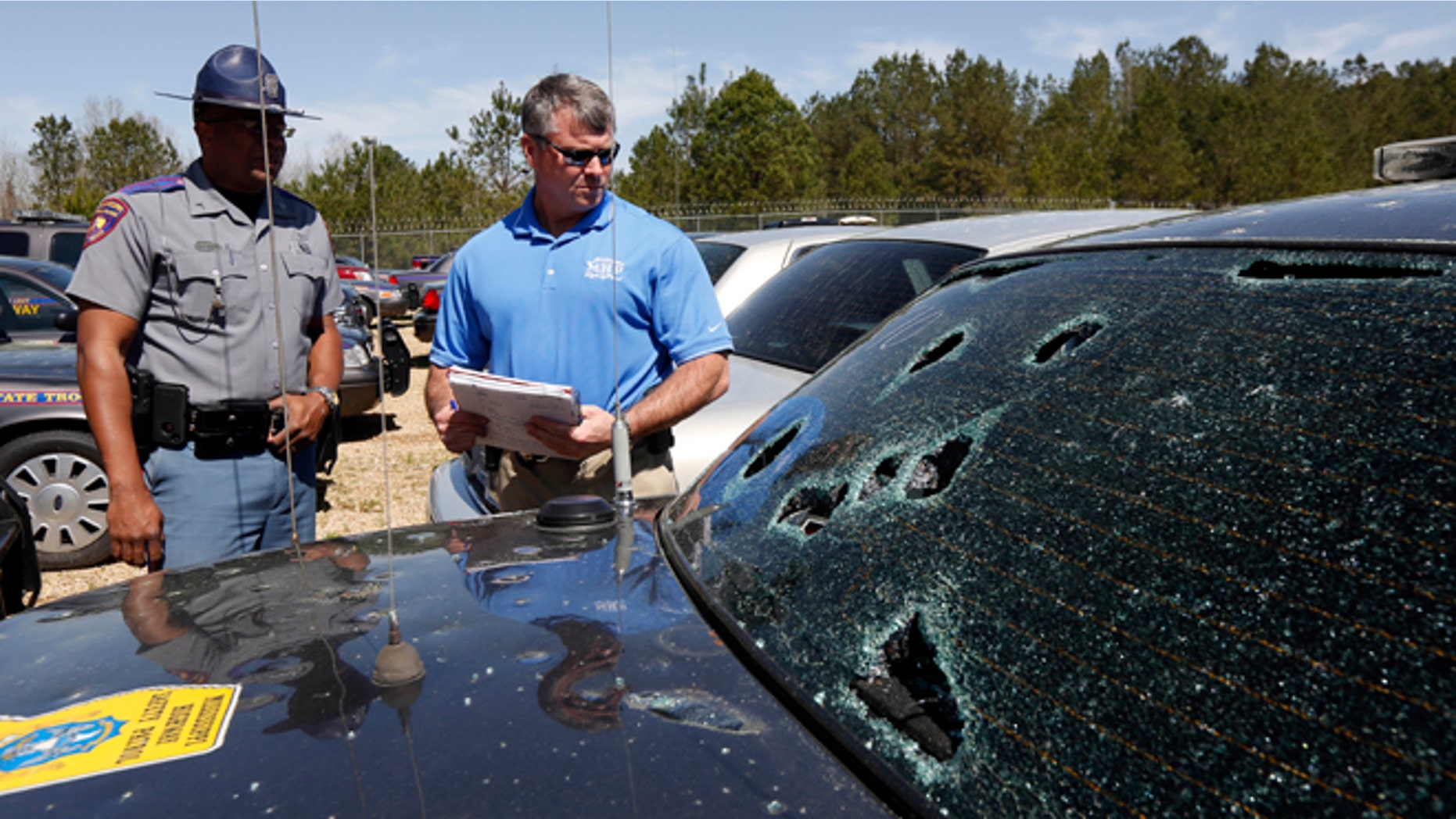 March 19: Mississippi Highway Patrol Lt. Col. Mike Holmes, right, and Cpl. Odis Easterling, survey the damage made by hail stones to a crusier in Pearl, Miss.