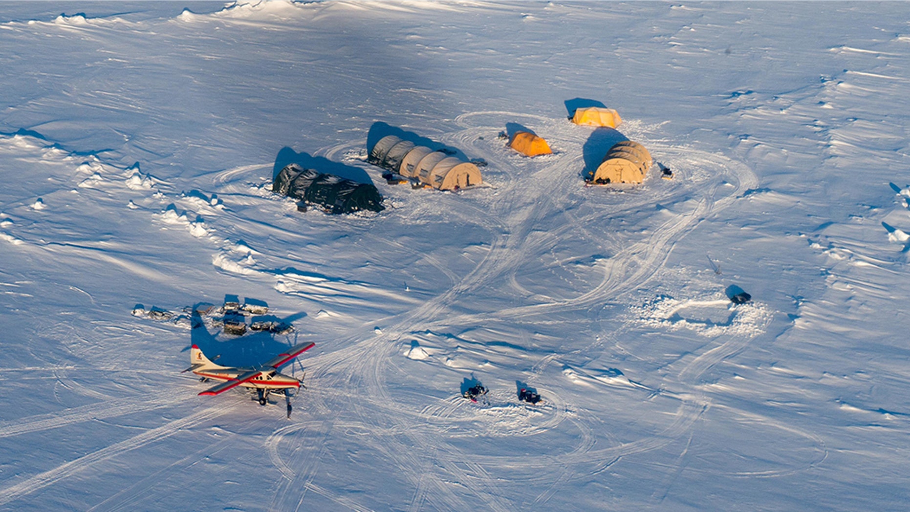 A helicopter flies over Arctic ice towards the Applied Physics Laboratory Ice Station in Alaska.