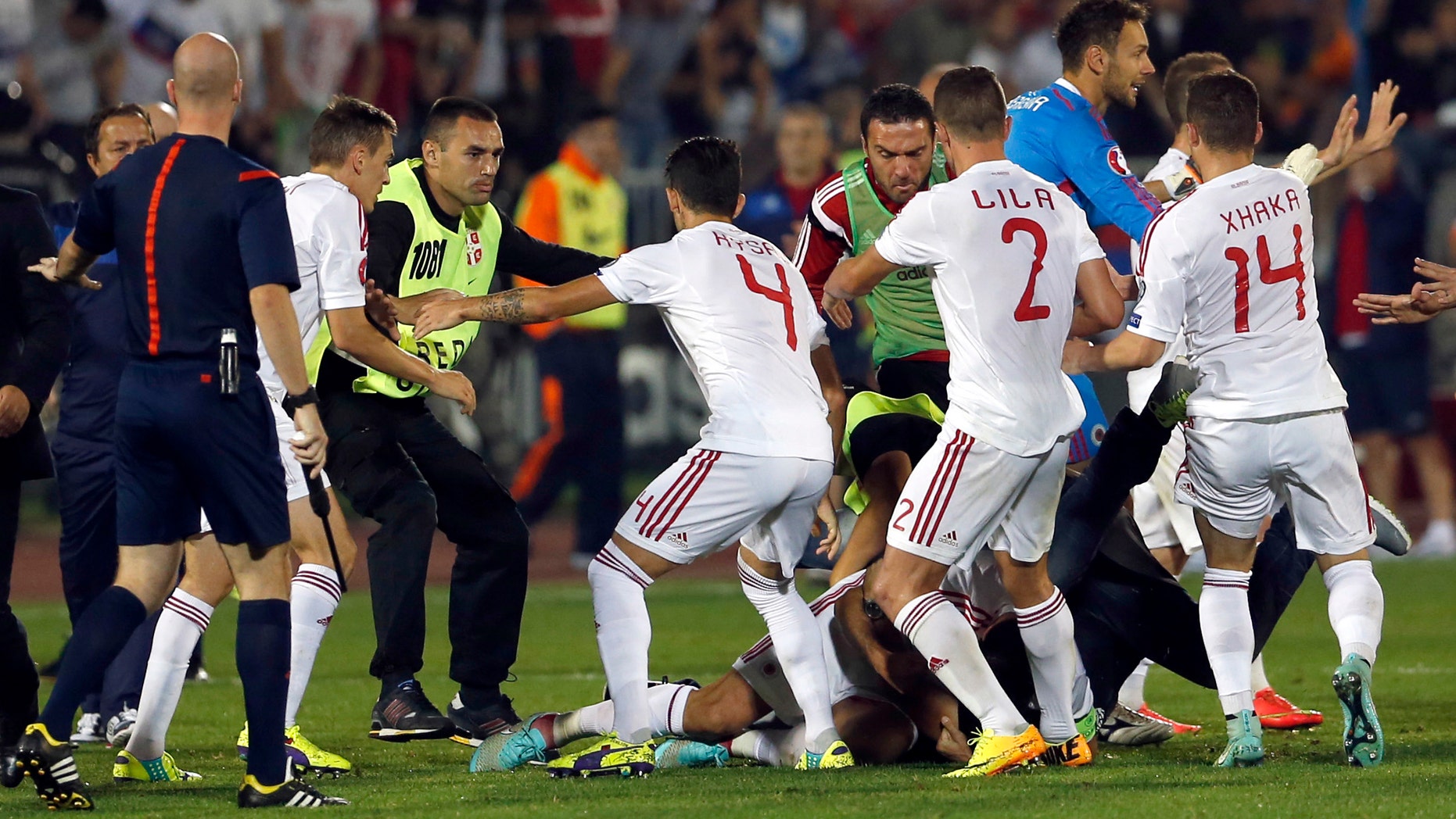A skirmish between Serbian and Albanian players breaks out on the pitch during the Euro 2016 Group I qualifying match between Serbia and Albania in Belgrade, Serbia, Tuesday, Oct. 14, 2014. The European Championship qualifier between Serbia and Albania was suspended on Tuesday after pitch skirmishes involving players and fans over an Albanian flag that was flown above the stadium by a drone. (AP Photo/Marko Drobnjakovic)