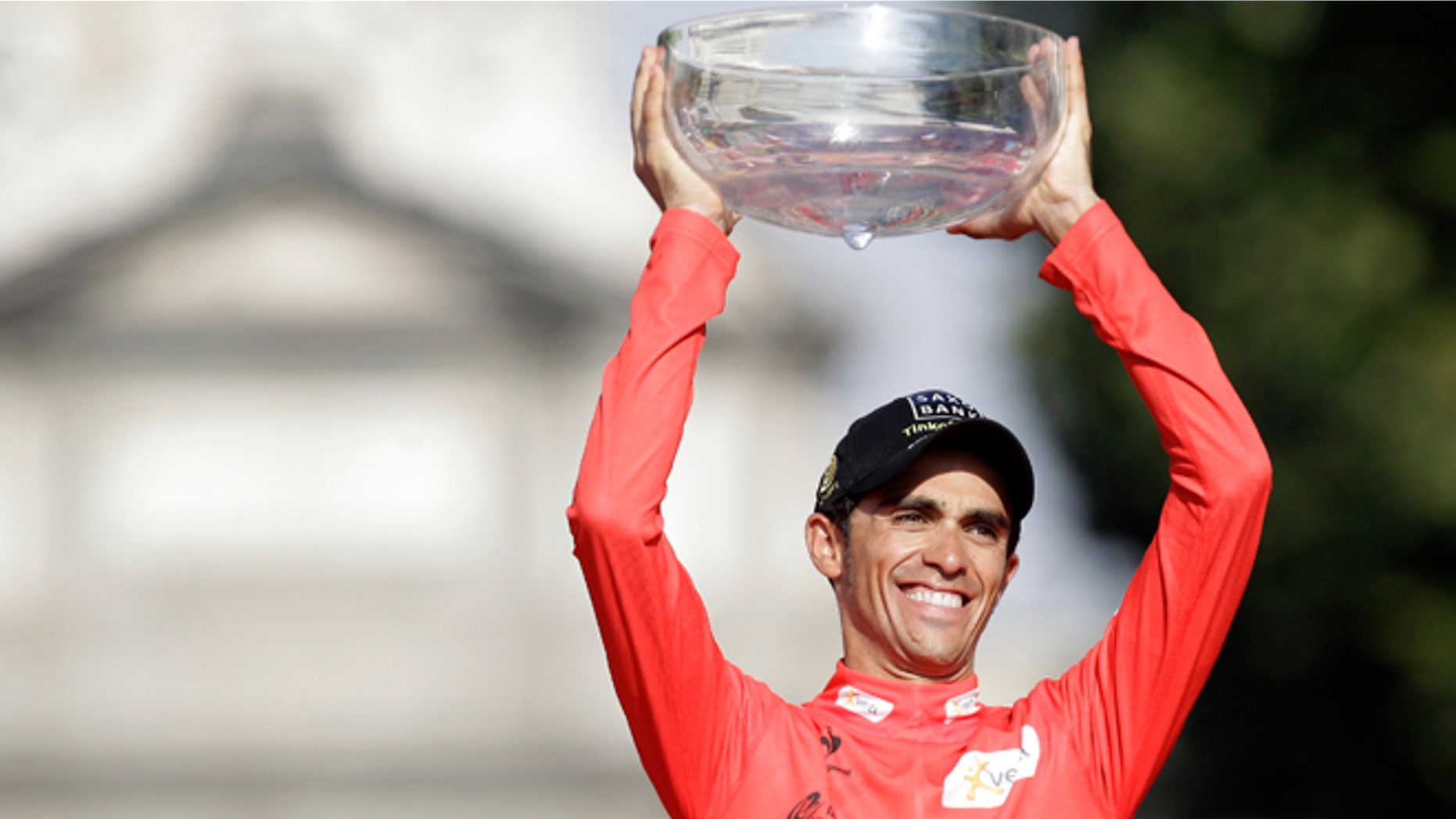 Saxo Bank Team cyclist Alberto Contador celebrates at the podium as he holds Spanish vuelta cycling race trophy after riding the final stage along 115 km (71 miles) from Cerdedilla to Madrid, on Sunday, Sept. 9, 2012. (AP Photo/Alberto Di Lolli)