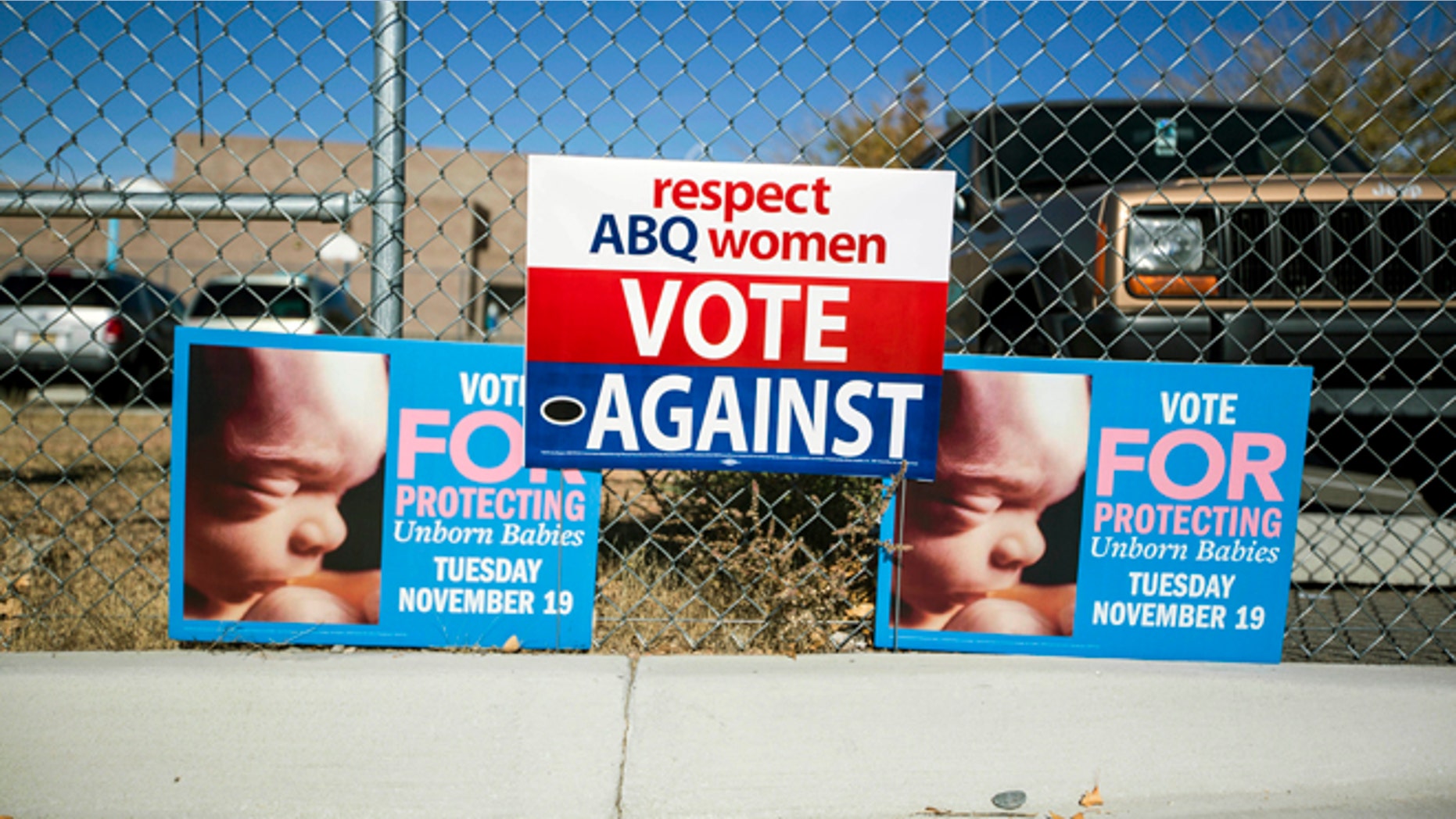 Signs advocating for and against a late term abortion ban hang on a fence outside of a voting site at Eisenhower Middle School in Albuquerque, N.M., Tuesday, Nov. 19, 2013. Albuquerque voters will decide whether to ban abortions after 20 weeks following an emotional and graphic campaign that has included protests and hundreds of thousands of dollars on television and radio ads that have brought out more than twice as many early voters as the recent mayoral elections. (AP Photo/Juan Antonio Labreche)
