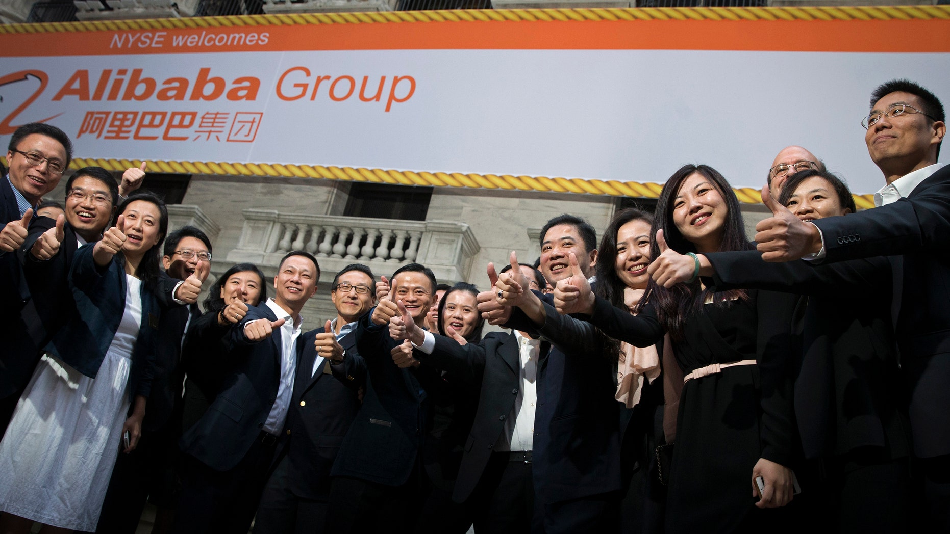 Alibaba Group Holding Ltd founder Jack Ma (C) and Joseph Tsai (center L), vice chairman and co-founder, pose with employees as they arrive for the company's initial public offering (IPO) under the ticker 'BABA,' at the New York Stock Exchange Sept. 19.