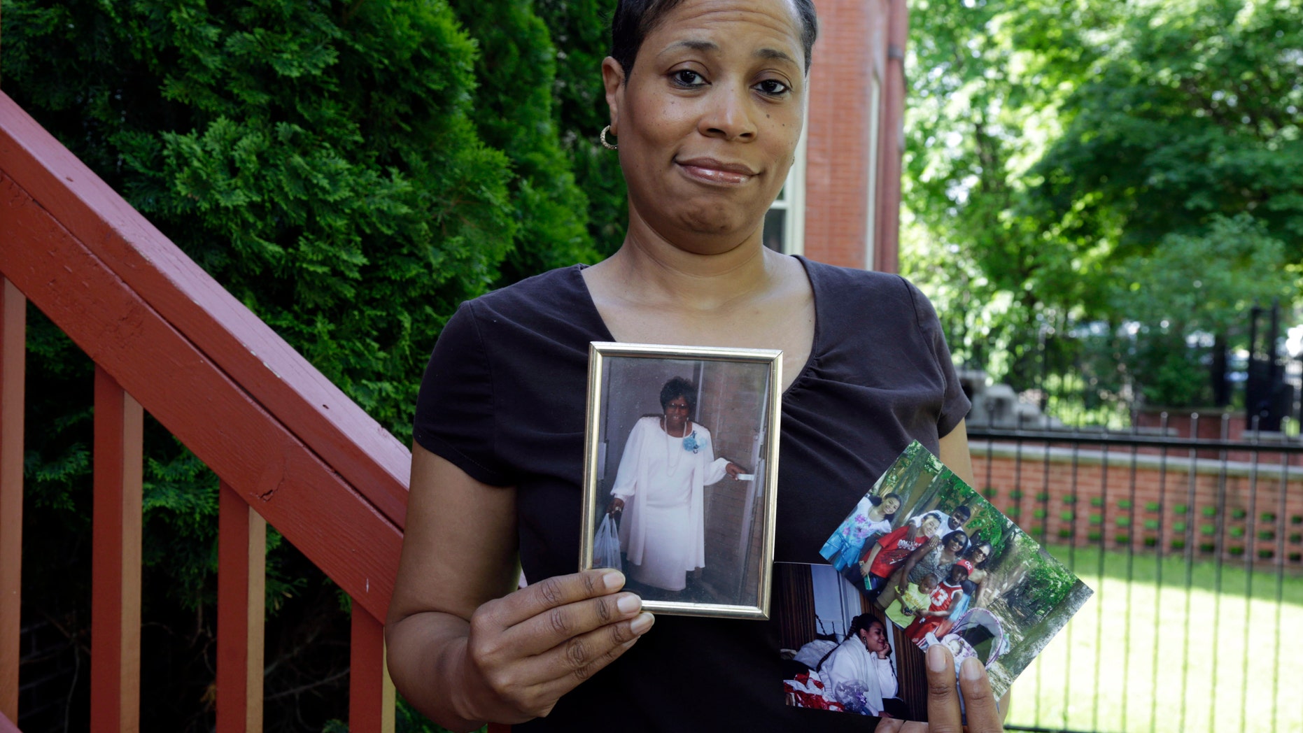 Breast cancer survivor Alicia Cook holds photos of family members who have also been afflicted by breast cancer, outside her home in Chicago. New research shows genetic breast cancer is more common in black women than previously thought. (AP Photo/M. Spencer Green)