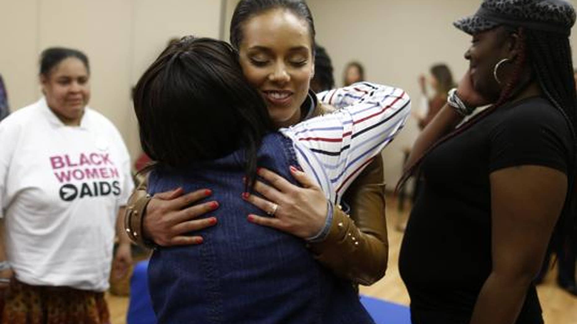 Grammy Award-winning singer Alicia Keys hugs HIV positive woman as she visits an HIV women's support group at United Medical Center in Washington, Monday, April 15, 2013. (AP Photo/Charles Dharapak)