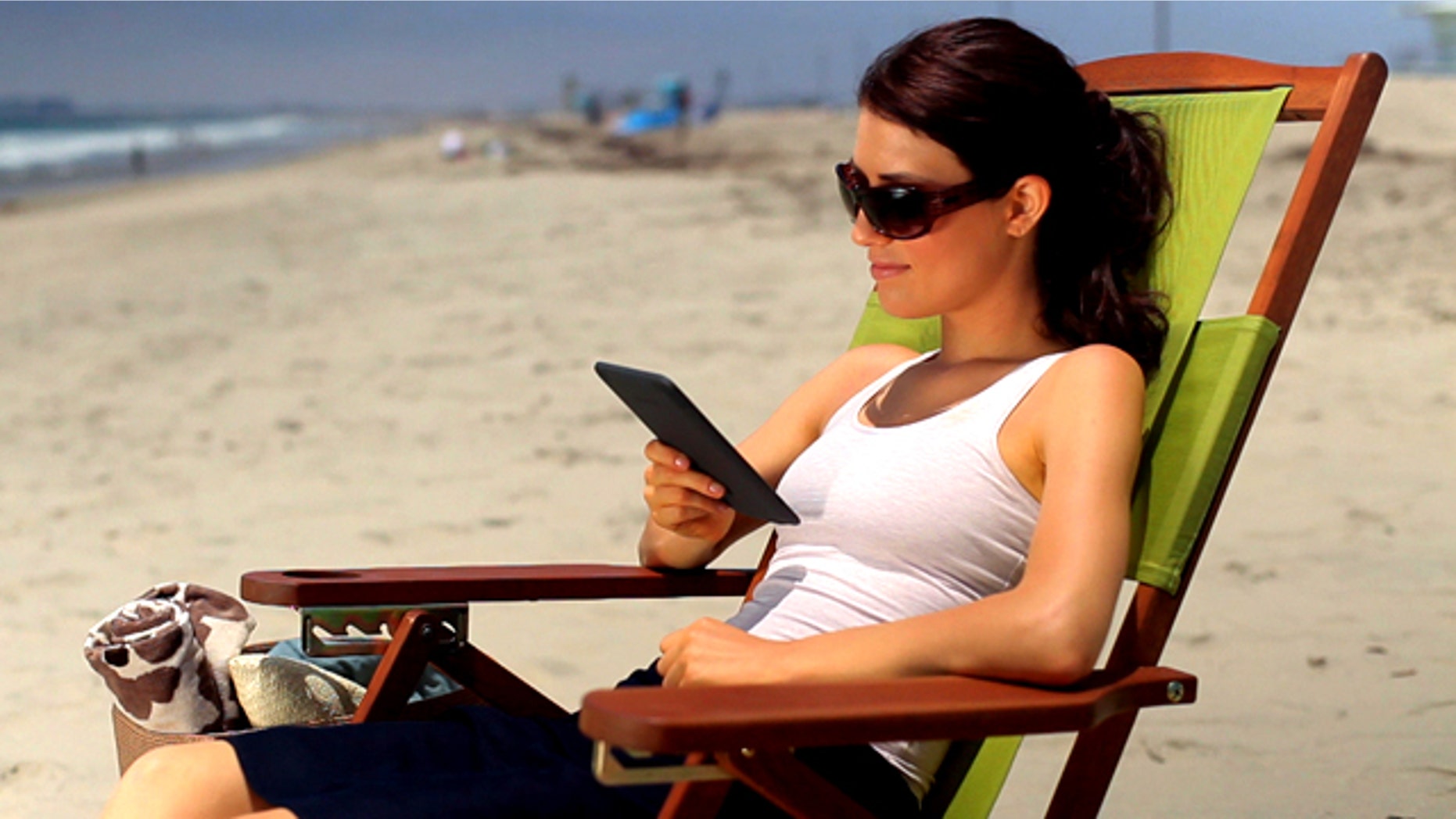 A woman reads an Amazon Kindle ebook reader at the beach. The Internet retail giant is widely expected to be planning a larger tablet PC to compete with the iPad..
