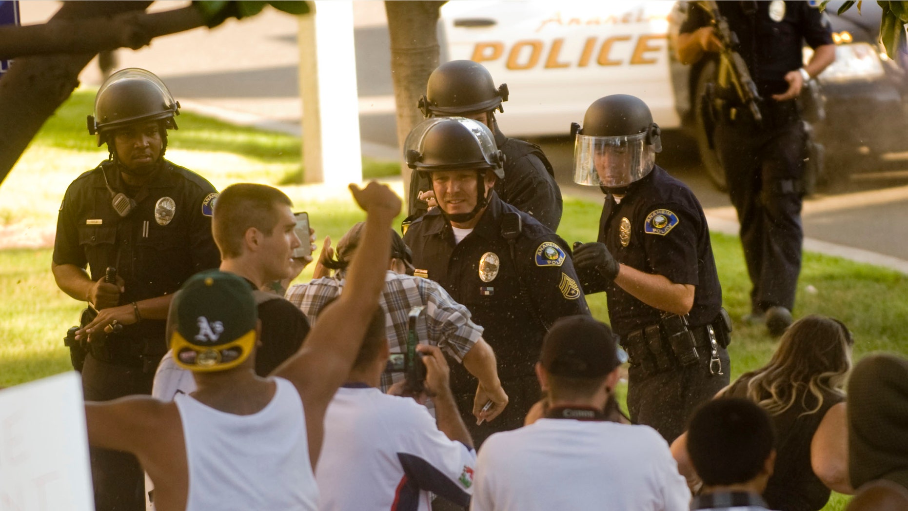 A group of Anaheim police officers try to hold back a crowd of protesters as they wait reinforcements Tuesday afternoon July 25, 2012, in Anaheim, Calif. (AP)