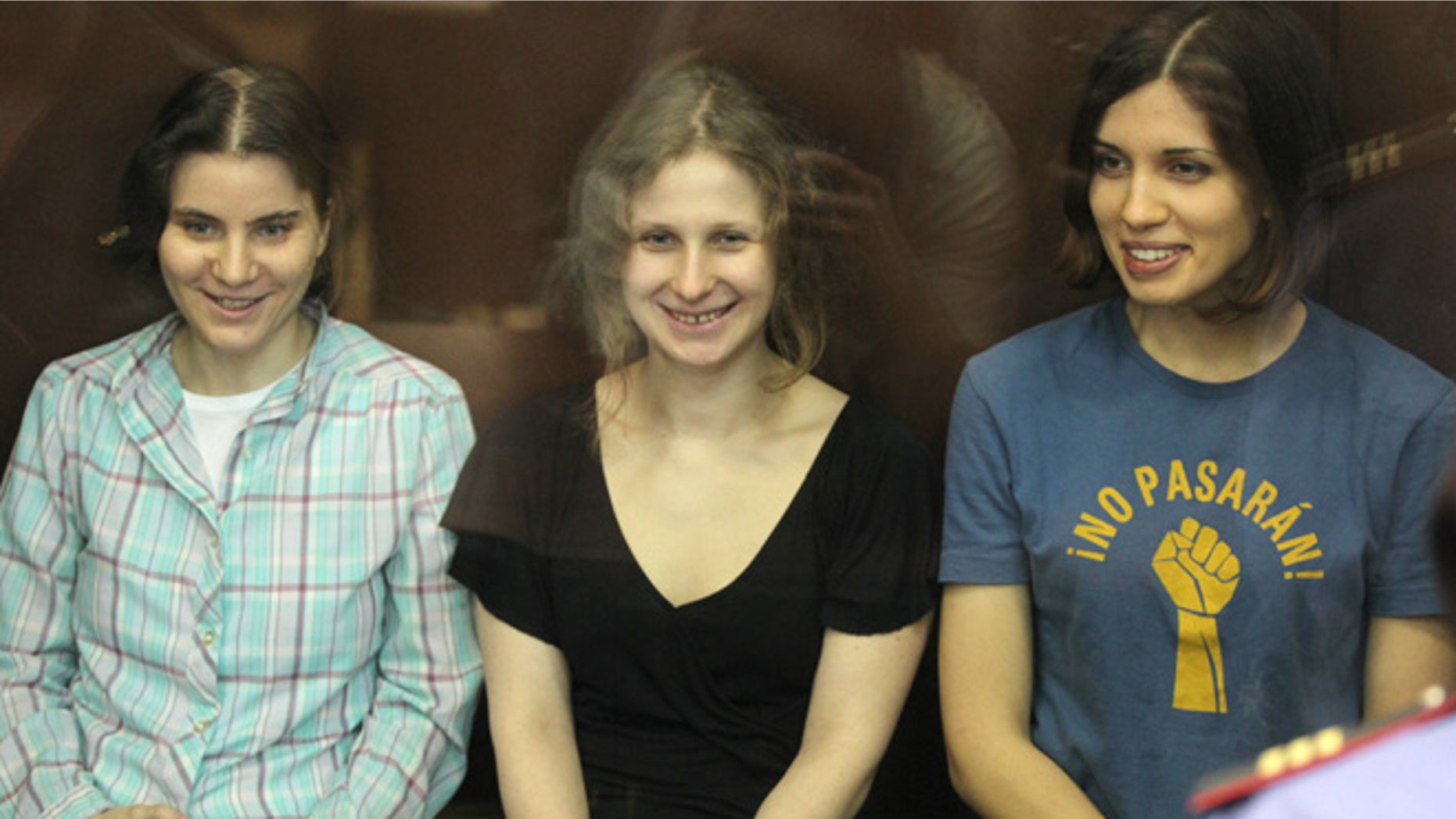 Aug. 17, 2012: Nadezhda Tolokonnikova, right, Yekaterina Samutsevich, left, and Maria Alekhina, center, members of feminist punk group Pussy Riot seen behind a glass wall at a court in Moscow, Russia.