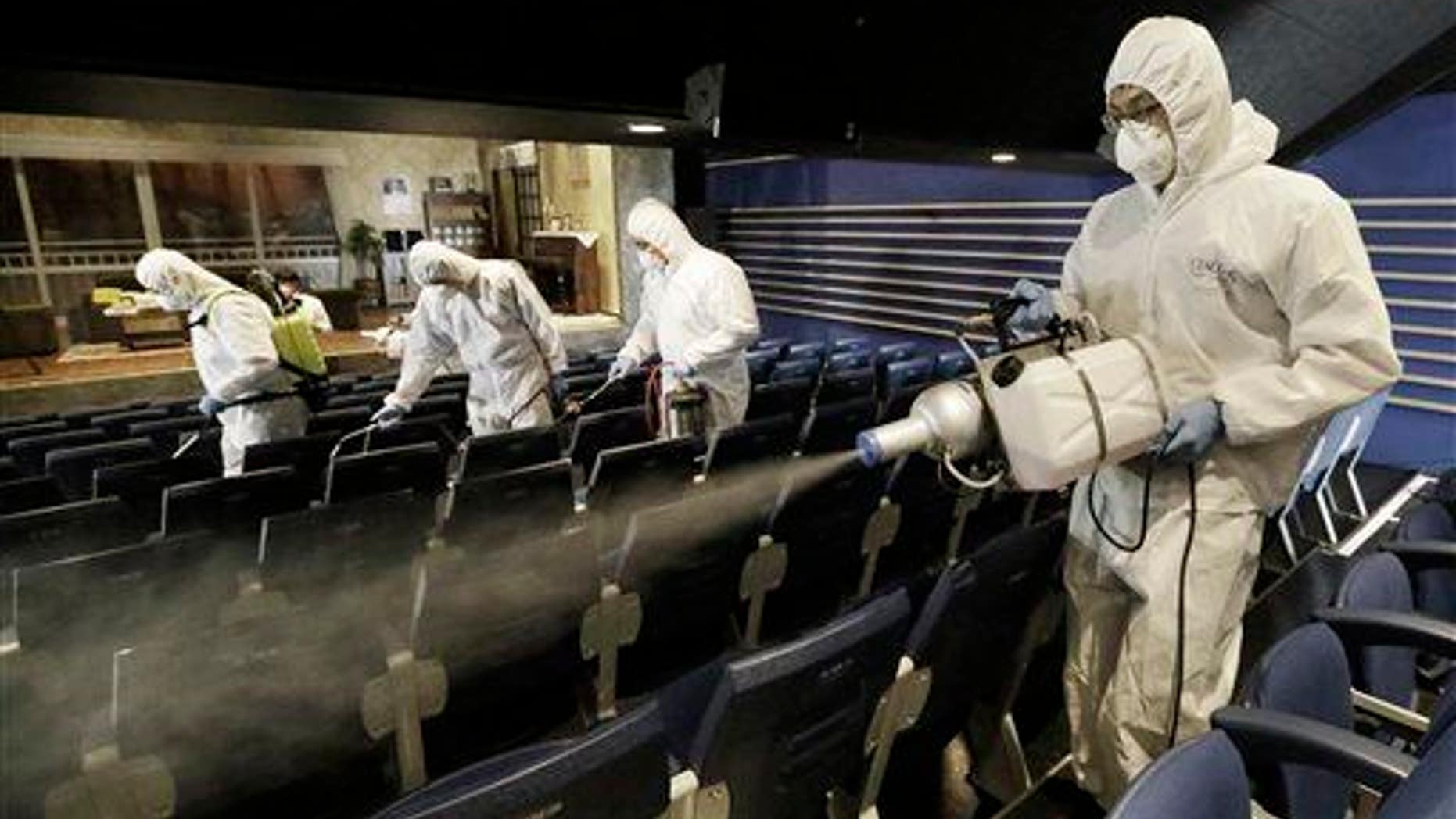 Workers wearing protective gear spray antiseptic solution as a precaution against the spread of the MERS virus at Uniplex Art Center in Seoul, South Korea, Thursday, June 17, 2015.