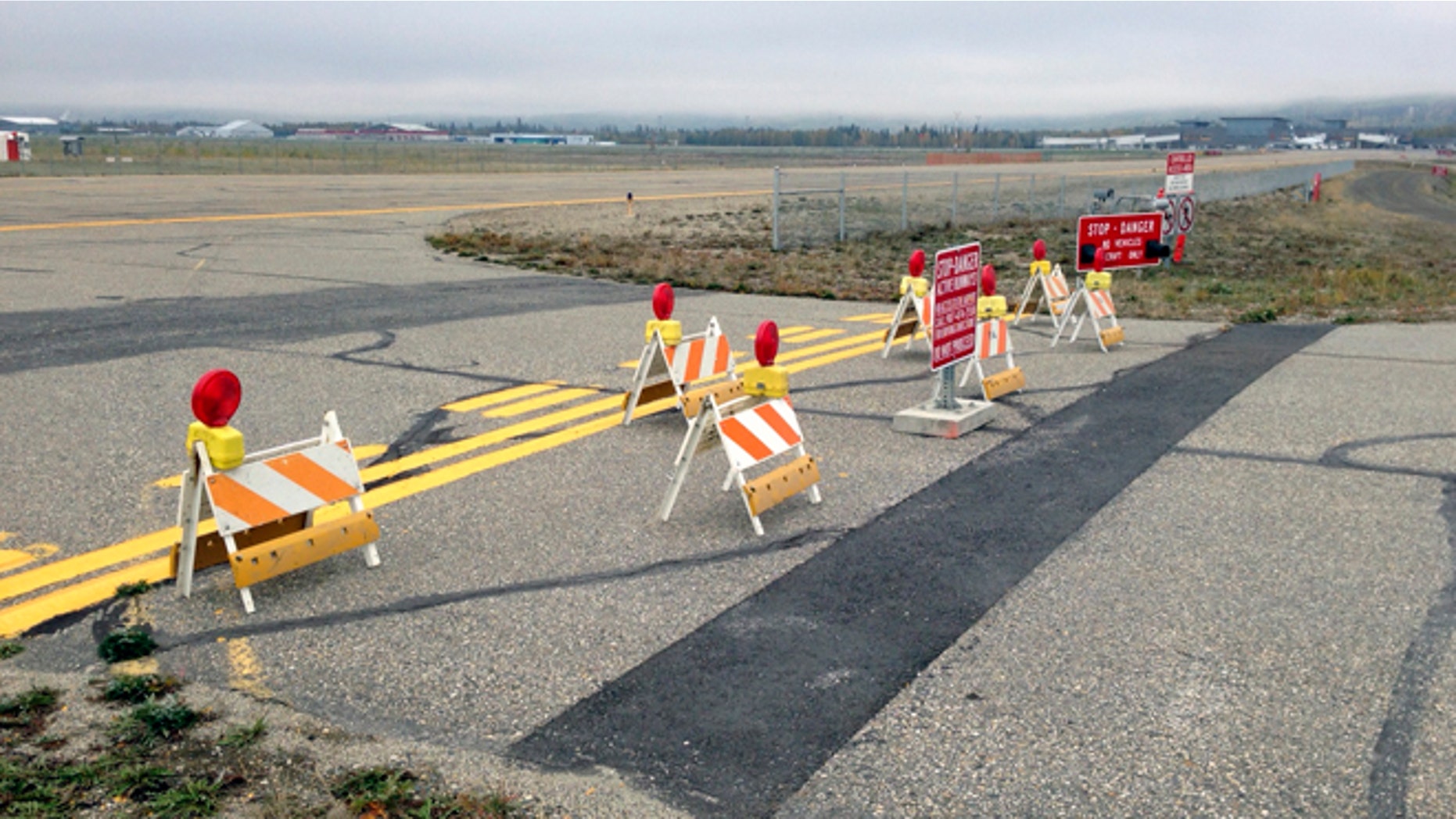 This Sept. 20, 2013 image provided by the Fairbanks International Airport shows the barricaded entrance to a taxiway, at Float Pond Road blocking access to Taxiway B in Fairbanks, Alaska. A glitch in the Apple Maps app on newer iPhones and iPads guides people up to this runway at Fairbanks International Airport instead of the proper route to the terminal. (AP Photo/Fairbanks International Airport)