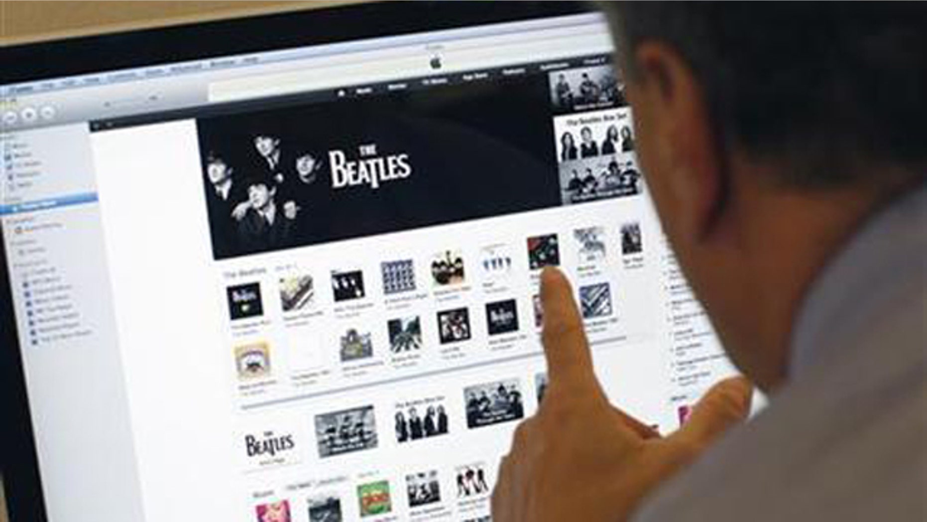 A man poses as he looks at music from the legendary band The Beatles on Apple's itunes music store website seen on an imac computer in New York, November 16, 2010.