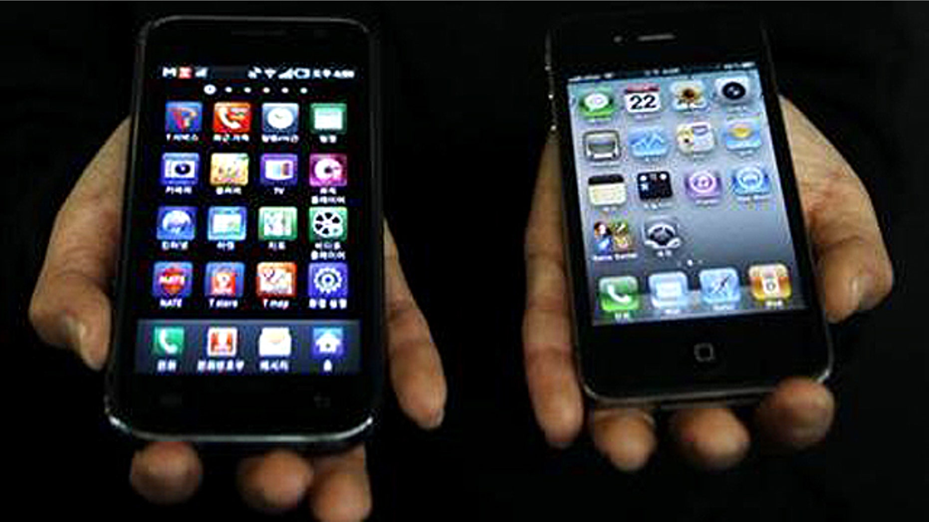 April 22, 2011: An employee of South Korean mobile carrier KT holds a Samsung Galaxy S (L) and an Apple iPhone 4 (R) at KT's headquarters in Seoul.