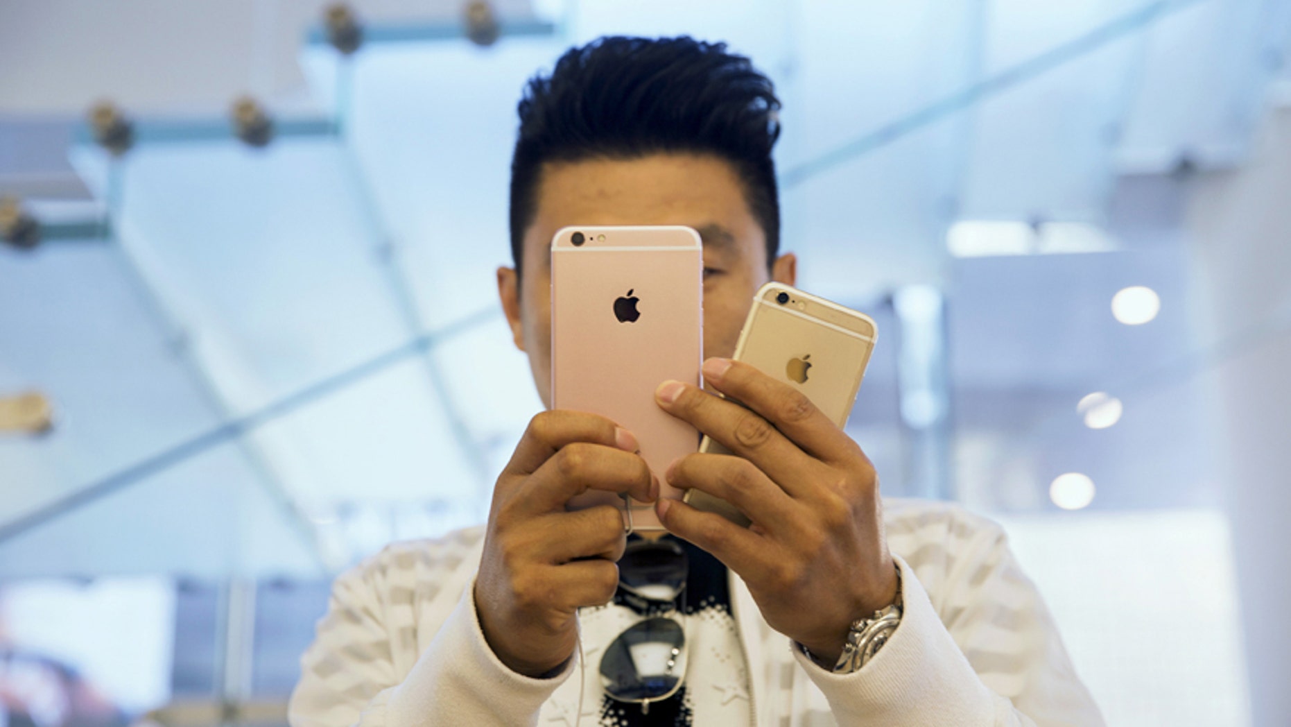 A man takes pictures as Apple iPhone 6s and 6s Plus go on sale at an Apple Store in Beijing, China Sept. 25, 2015.