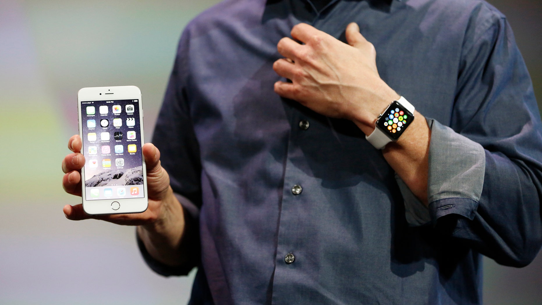 Apple CEO Tim Cook wears the Apple Watch and shows the iPhone 6 Plus during an Apple event at the Flint Center in Cupertino, California.