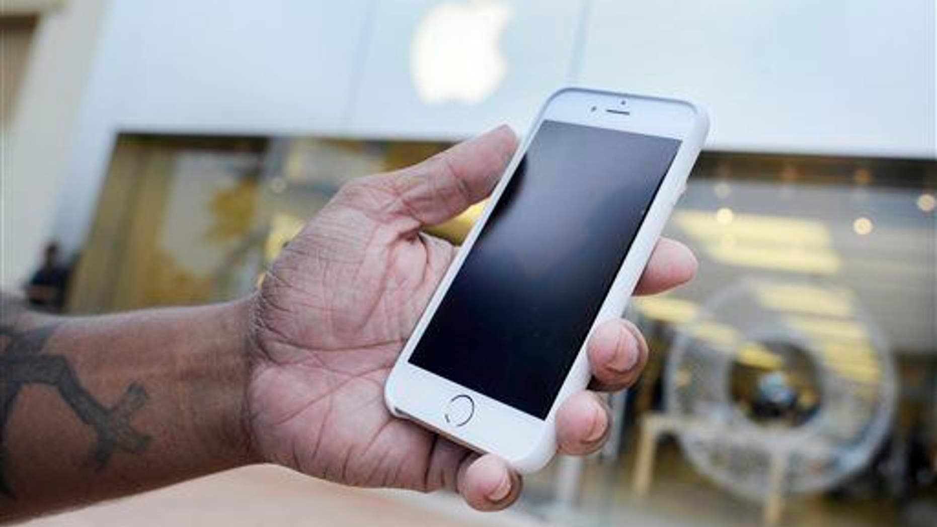 A customer holds his new iPhone 6 at an Apple Store in Augusta, Ga.