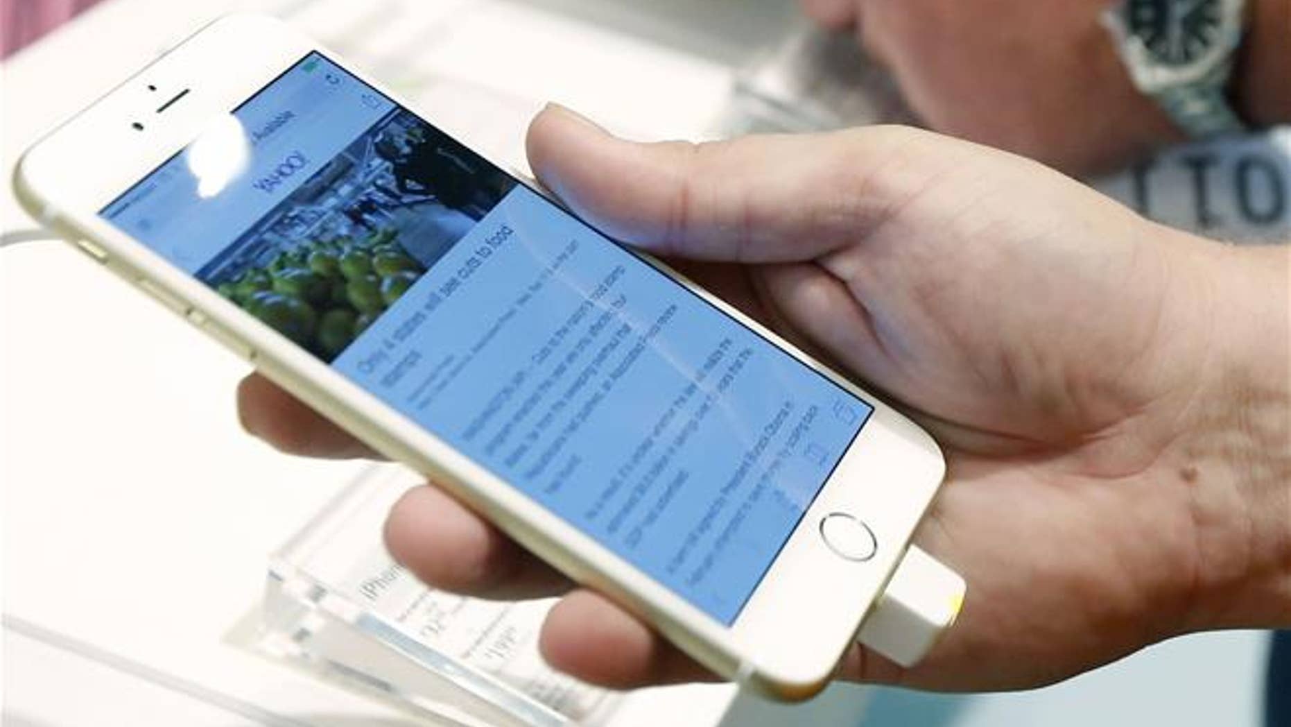In this Sept. 19, 2014, file photo, a customer looks at the screen size on an iPhone 6 Plus.