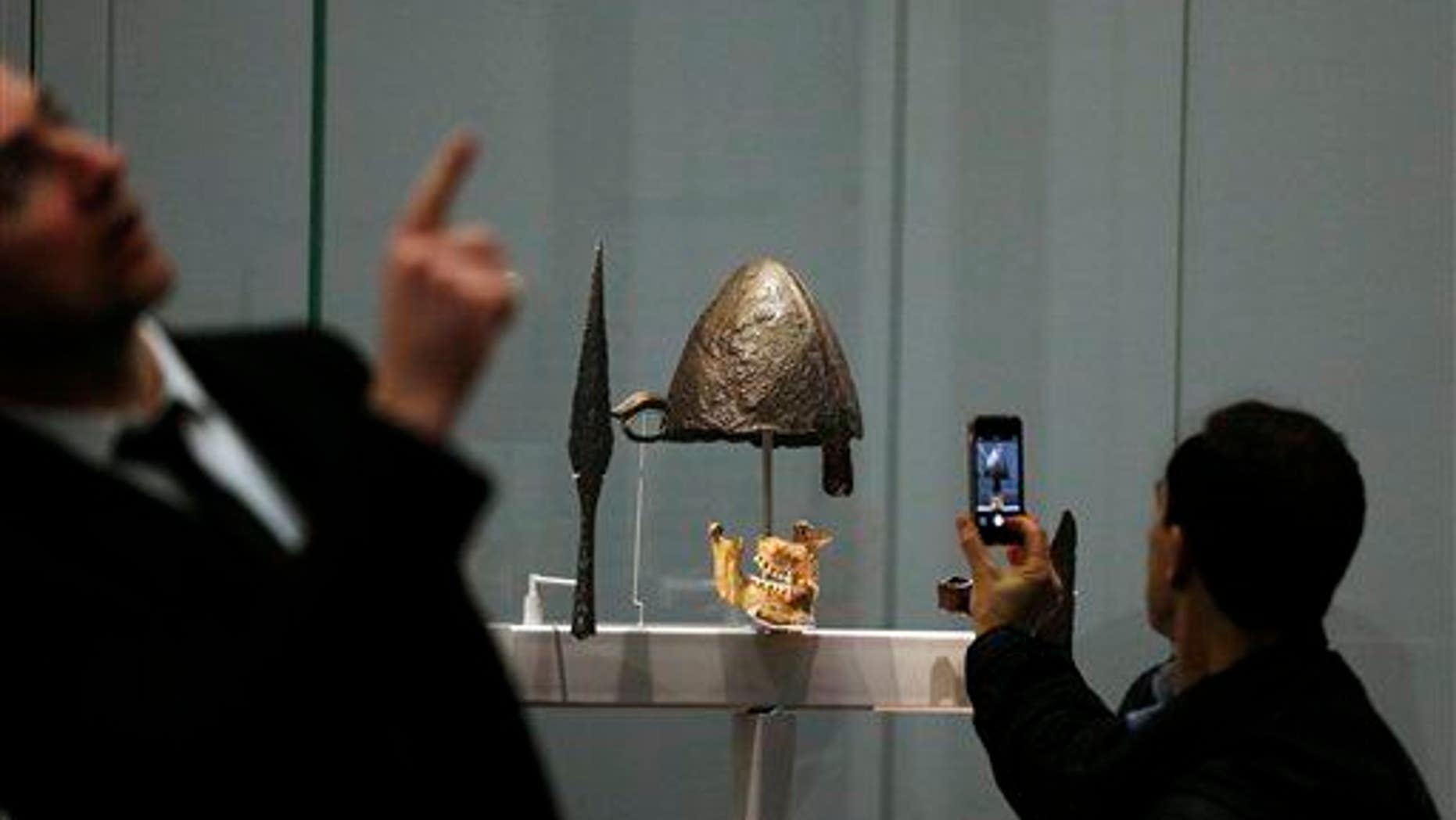 A visitor takes pictures at a display of helmets and weapons at an exhibition entitled 'Vikings: Life and Legend' at the British Museum in central London, Tuesday, March 4, 2014.