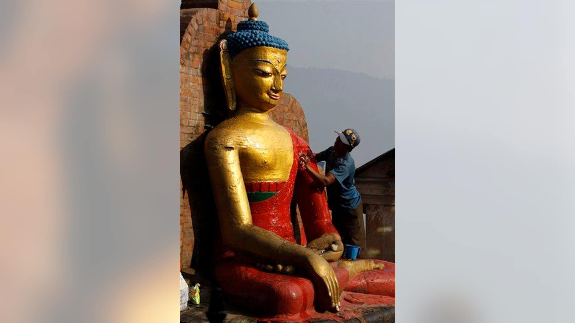 A Buddhist devotee cleans a statue of Buddha at Swayambhunath Stupa ahead of a celebration in Kathmandu, Nepal, on May 16, 2011.