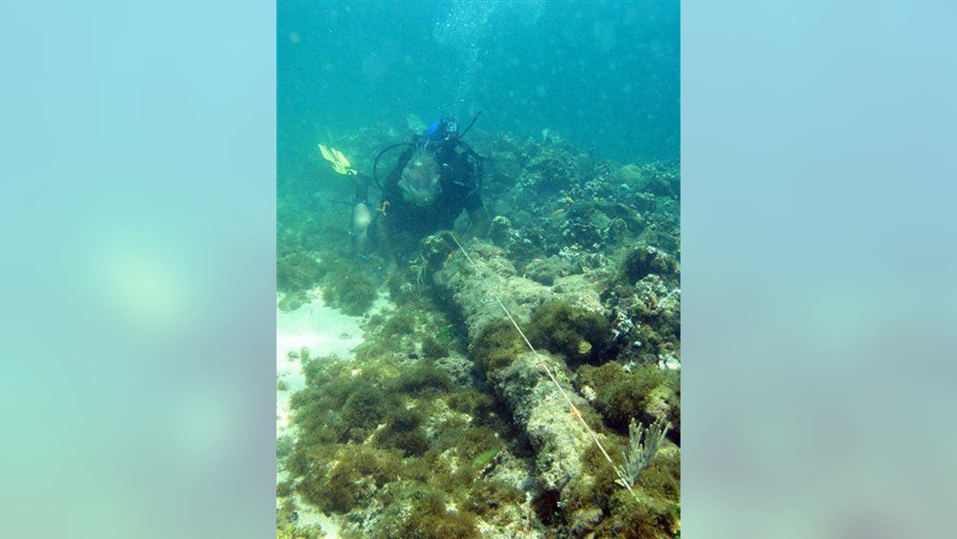 In this May 2003 photo, a diver measures a cannon adjacent to a ballast pile off the coast of Haiti at a site explorer Barry Clifford says could be the wreckage of Columbus's vessel the Santa Maria.