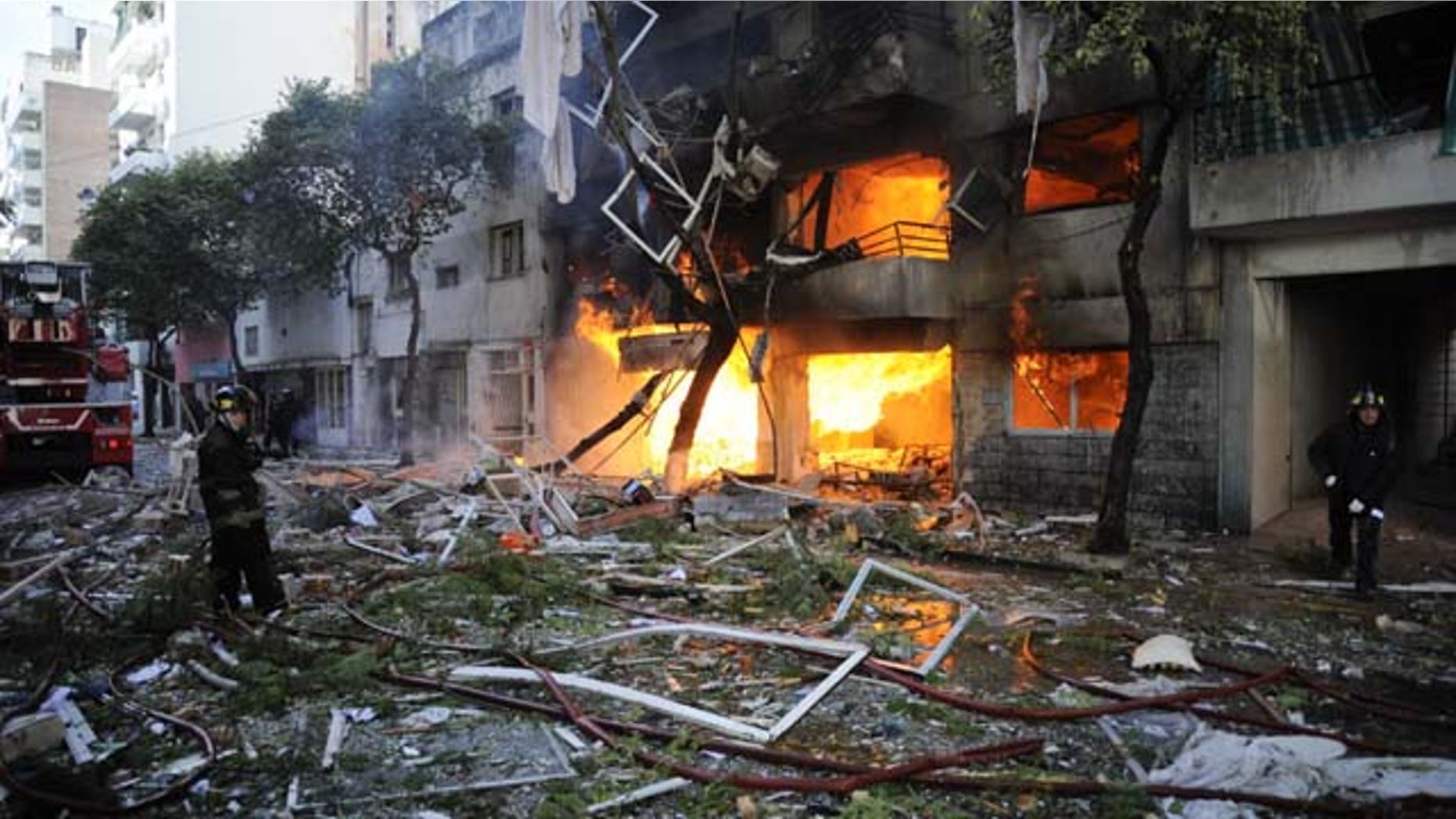 August 6, 2013: Firemen stand in debris caused by a gas explosion that has severely damaged a multi-story apartment building in Rosario, Argentina. The explosion ripped off the building’s facade and also damaged other buildings for blocks around. (AP Photo)