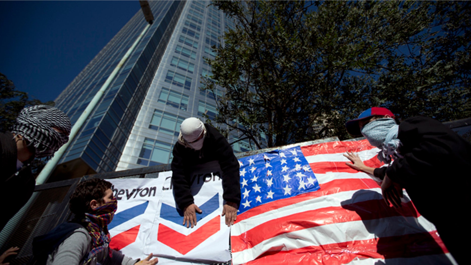 Demonstrators place a U.S. flag and a Chevron sign on a fence in front of Argentina's state-controlled YPF oil company headquarters to protest a deal between YPF and U.S. oil company Chevron in Buenos Aires, Argentina, Tuesday, July 16, 2013. YPF, which was expropriated in 2012 from Spain's Repsol, is finalizing the details of an agreement with Chevron which would invest in the first pilot for massive exploration for unconventional oil and gas in the Vaca Muerta region. (AP Photo/Victor R. Caivano)