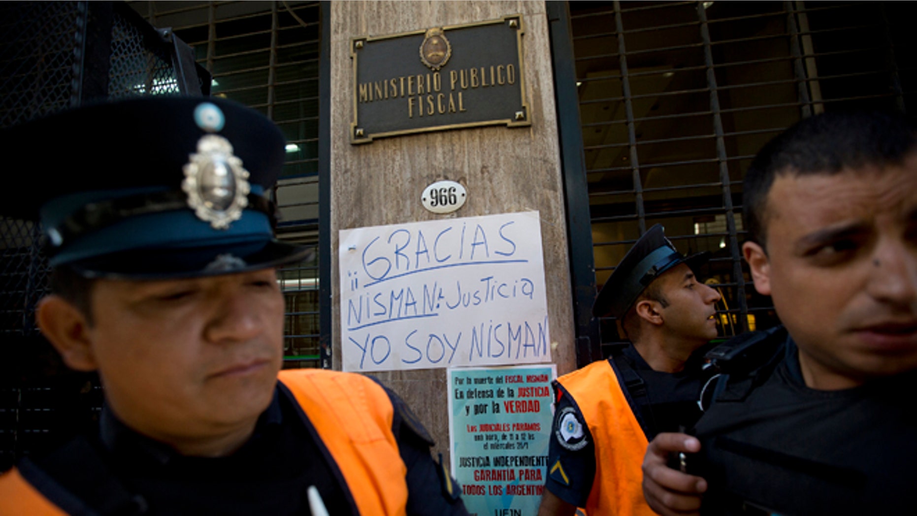 Policemen stand guard next to a sign that reads in Spanish; "Thanks Nisman. Justice. I am Nisman," outside the prosecutor's office investigating the death of Alberto Nisman, a prosecutor found dead in his apartment, in Buenos Aires, Argentina, Thursday, Jan. 22, 2015. The death of the prosecutor who had accused Argentinas President Cristina Fernandez of a criminal conspiracy came under mounting questions Wednesday with the discovery that the apartment where he was found dead had not been securely locked and had a third entrance. (AP Photo/Rodrigo Abd)