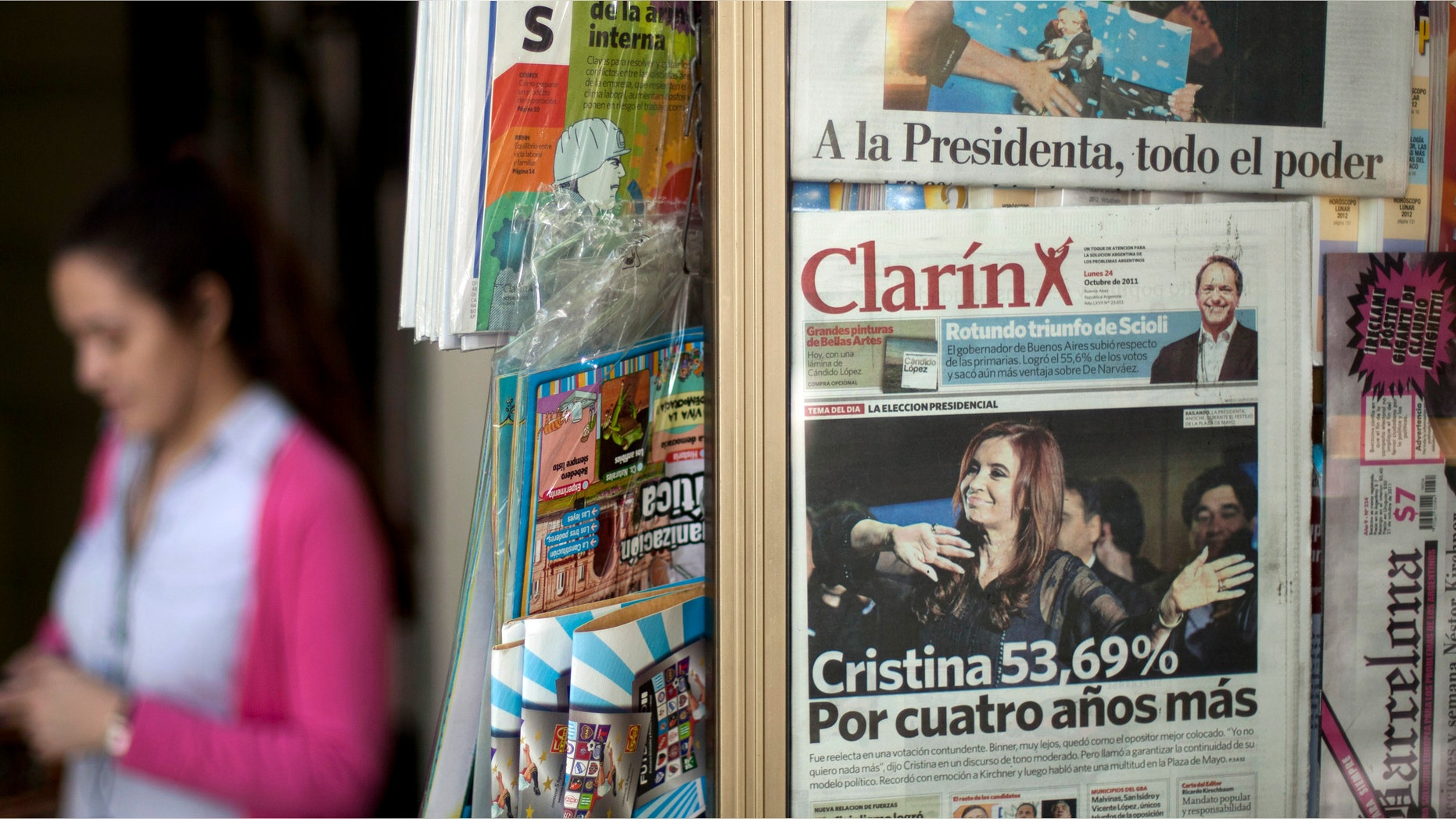 FILE - In this Oct. 24, 2011 file photo, a woman walks by a newspaper stand that displays Argentina's largest circulating daily newspaper the Clarin in Buenos Aires, Argentina. Argentinas government on Saturday, Sept. 22, 2012 gave one of its leading media critics, Grupo Clarin, a Dec. 7 deadline to sell off most of its broadcast stations, saying 7D will stand for diversity and democracy as the day when media monopolies will no longer be able to put themselves above the law. (AP Photo/Victor R. Caivano, File)