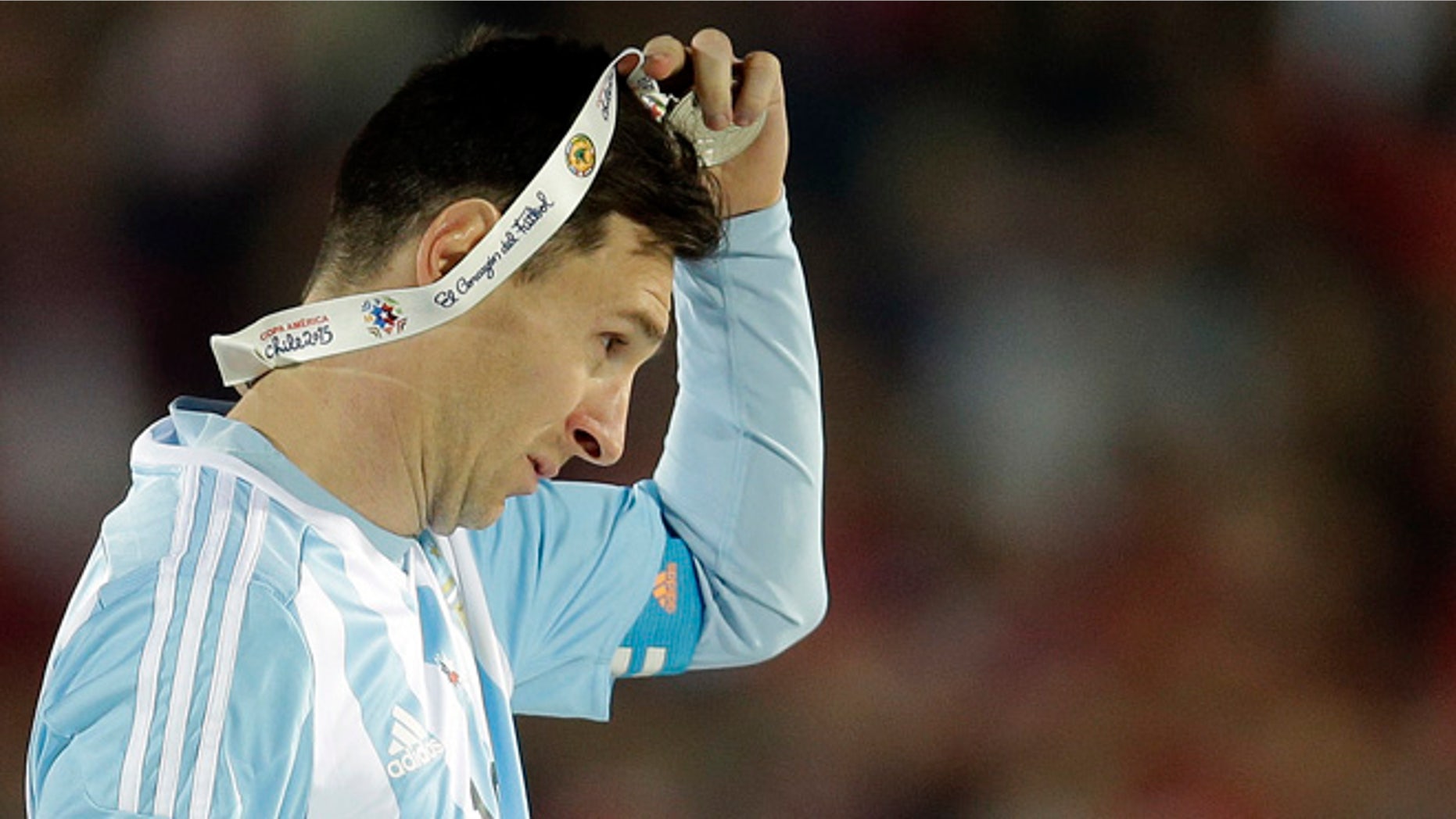 FILE - In this July 4, 2015 file photo, Argentina's Lionel Messi takes off the Copa America silver medal after the final game with Chile at the National Stadium in Santiago, Chile. Messi's shocking decision to stop playing for Argentina could further hurt his already tarnished legacy with his national team. If Messi sticks to his announcement, made in the heat-of-the-moment shortly after Argentina's penalty shootout loss to Chile in Sunday's Copa America final on June 26, 2016, Argentina will be left dwelling on the fact that it was not able to win any significant title while having one of the best players of all time. (AP Photo/Natacha Pisarenko, File)