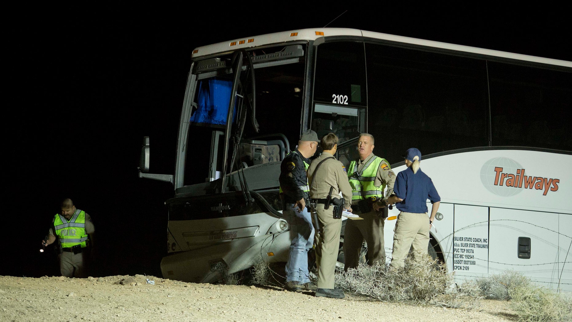 Oct. 19, 2012: Arizona Highway Patrol officers examine the exterior of a tour bus that careened off the highway and crashed off northbound Highway 93.