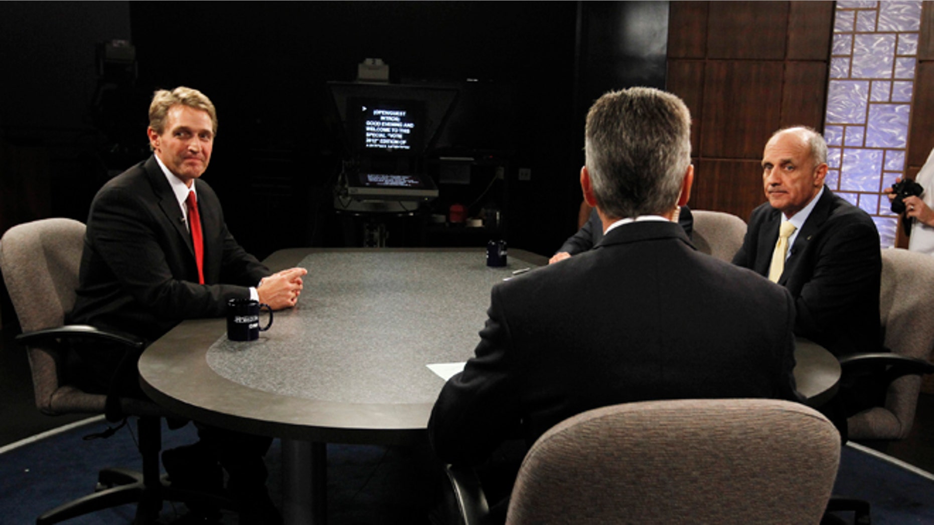 Rep. Jeff Flake, R-Ariz., left, and Democrat Richard Carmona, right, both listen to moderator Ted Simons, center, host and managing editor of Arizona Horizon at Eight, Arizona PBS, as he discusses the rules in the studio prior to an Arizona U.S. Senate debate Wednesday, Oct. 10, 2012, in Phoenix. The candidates are vying for the seat left open by retiring Sen. Jon Kyl, R-Ariz.(AP Photo/Ross D. Franklin)