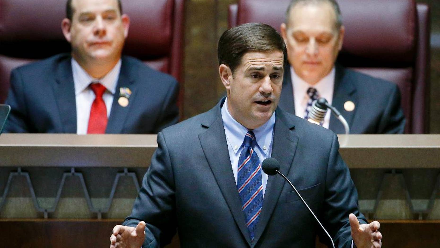 Arizona Republican Gov. Doug Ducey, front, gives his state-of-the-state address as Arizona House speaker David Gowan, left, R-Sierra Vista, and Arizona Senate President Andy Biggs, right, R-Gilbert, listen at the Arizona Capitol Monday, Jan. 12, 2015, in Phoenix. (AP Photo/Ross D. Franklin)