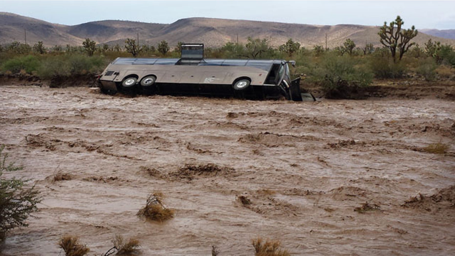 July 28, 2013: This photo released by the Northern Arizona Consolidated Fire District shows a Las Vegas-bound tour bus lies on its side in a flooded desert wash near Dolan Springs, Ariz. after being swept away by floodwaters amid heavy rains. (AP Photo)