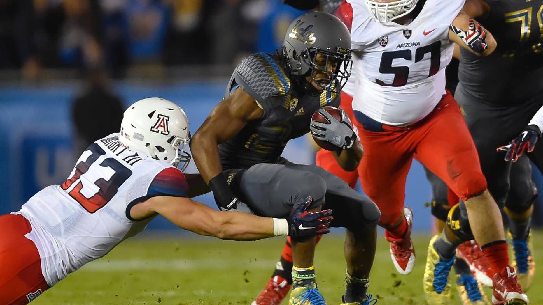 Arizona linebacker Scooby Wright III (33) and linebacker Cody Ippolito (57) close in on UCLA running back Paul Perkins, center, as he rushes during the first half of an NCAA college football game, Saturday, Nov. 1, 2014, in Pasadena, Calif. (AP Photo/Gus Ruelas)