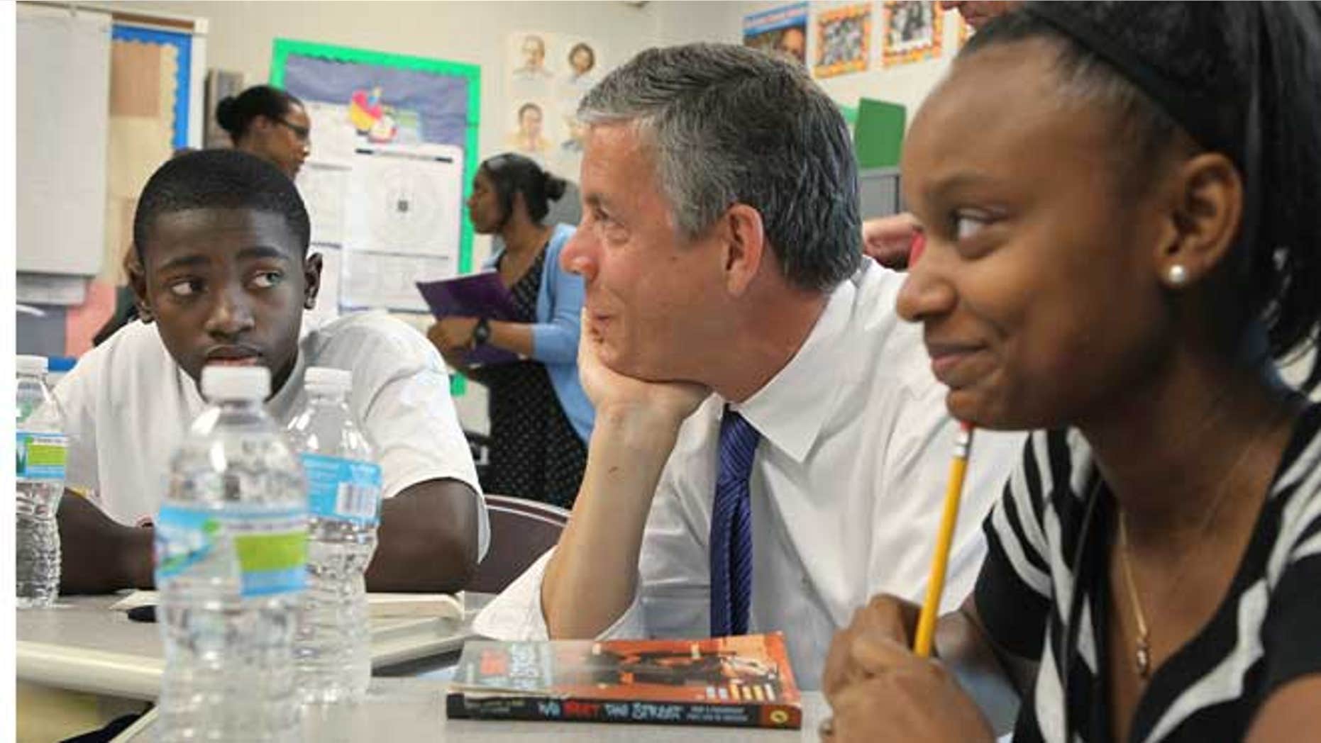 In this Monday, June 25, 2012 file photo, during a fact-finding tour of Vashon High School, U.S. Secretary of Education Arne Duncan, center, listens to eighth-grade students Delvion Mitchell, 14, and Makayla Lewis, 14, as they discuss social issues they have encountered at school and what they have learned from them, in St. Louis.