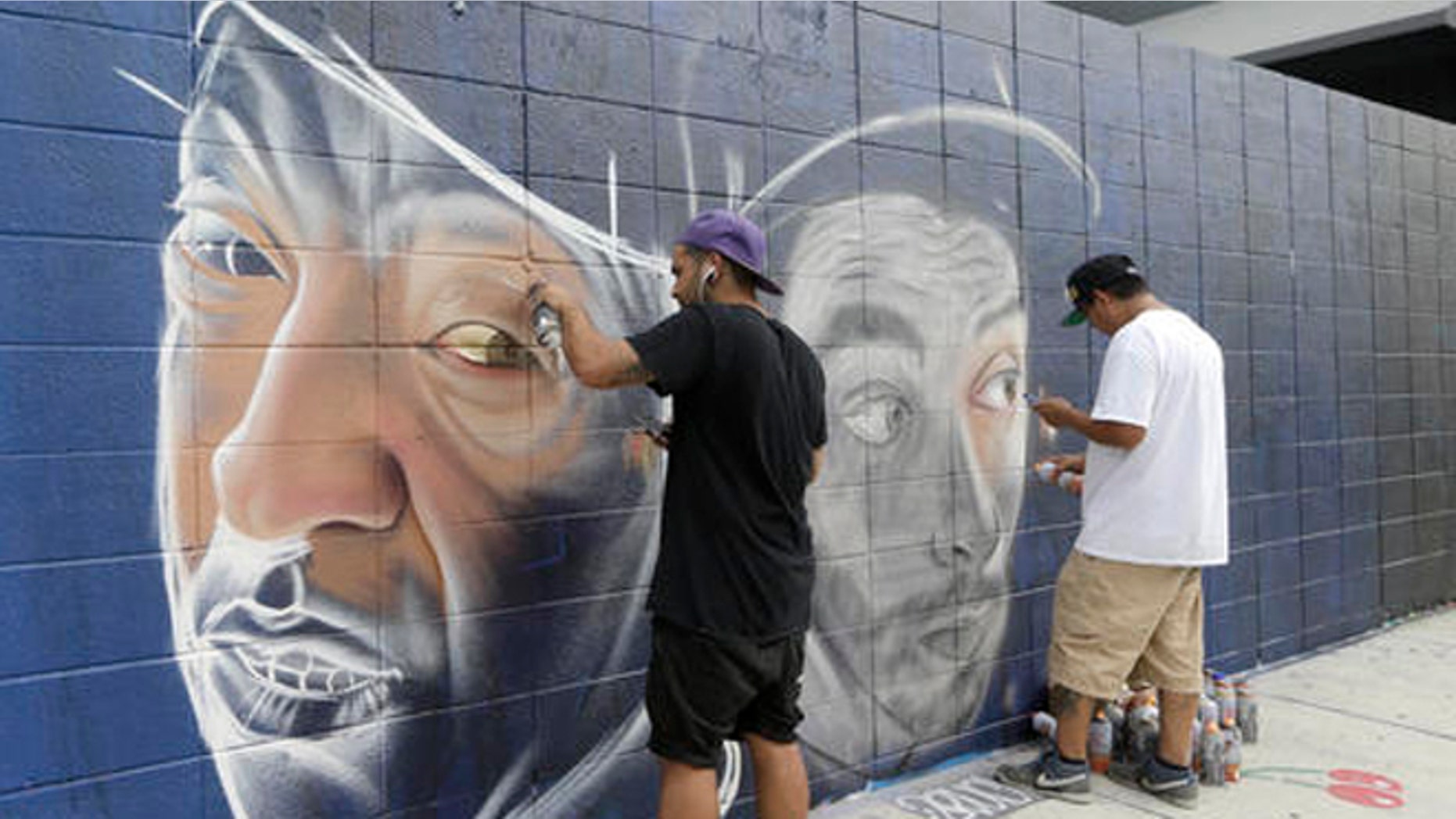 Artists Theo Magma, of Spain, left, and Koka, of Mexico, right, work on a mural, Friday, Dec. 2, 2016, in the Wynwood Art District in Miami, as the annual Art Basel festival continues, featuring poolside parties, blocks of art fairs and outdoor red carpet events. This marks the 15th year that Art Basel has been held in the Miami area. (AP Photo/Alan Diaz)