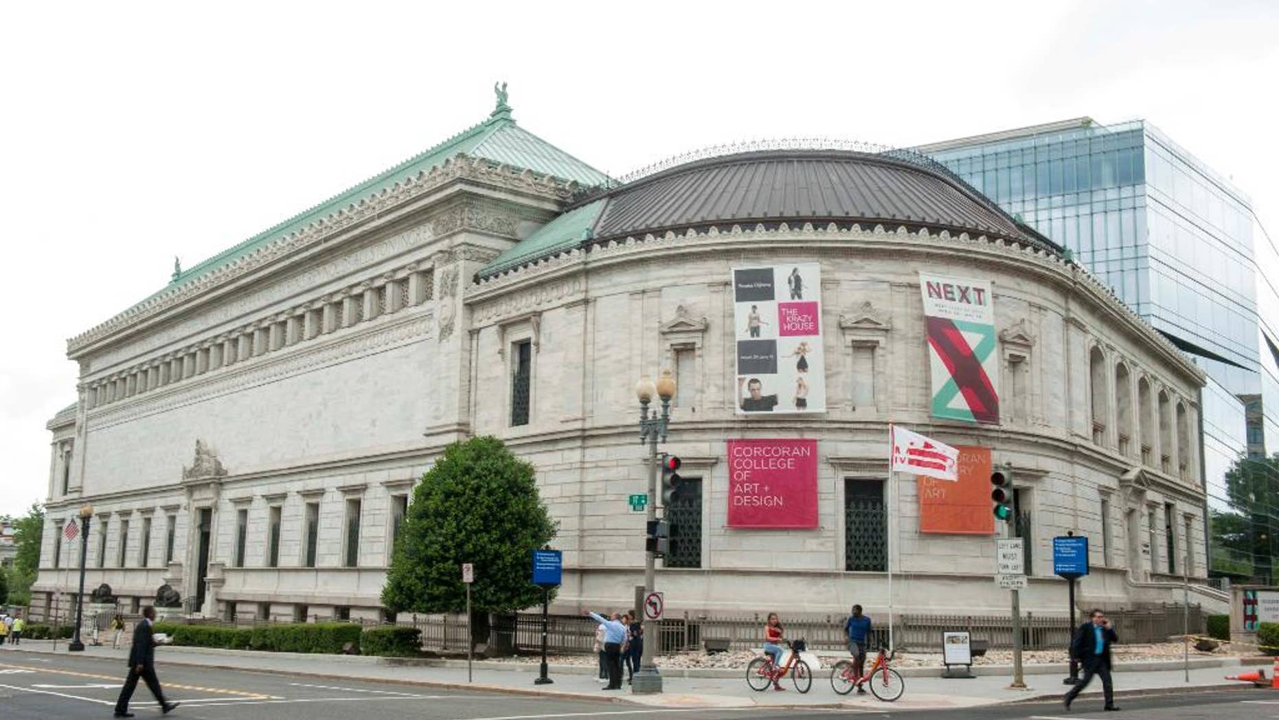 FILE - This May 15, file photo shows pedestrians passing the Corcoran Gallery of Art in Washington. Attorneys are set to make closing arguments in a case that will determine the future of one of the nation's oldest museums and one of the few independent art galleries in the nation's capital. Trustees of the Corcoran Gallery of Art are seeking to merge the museum and its college into George Washington University and the National Gallery of Art, dissolving the independent Corcoran after years of financial troubles. A group of current students and faculty has fought the merger in court, arguing there are ways to save the Corcoran. (AP Photo/Kevin Wolf, File)
