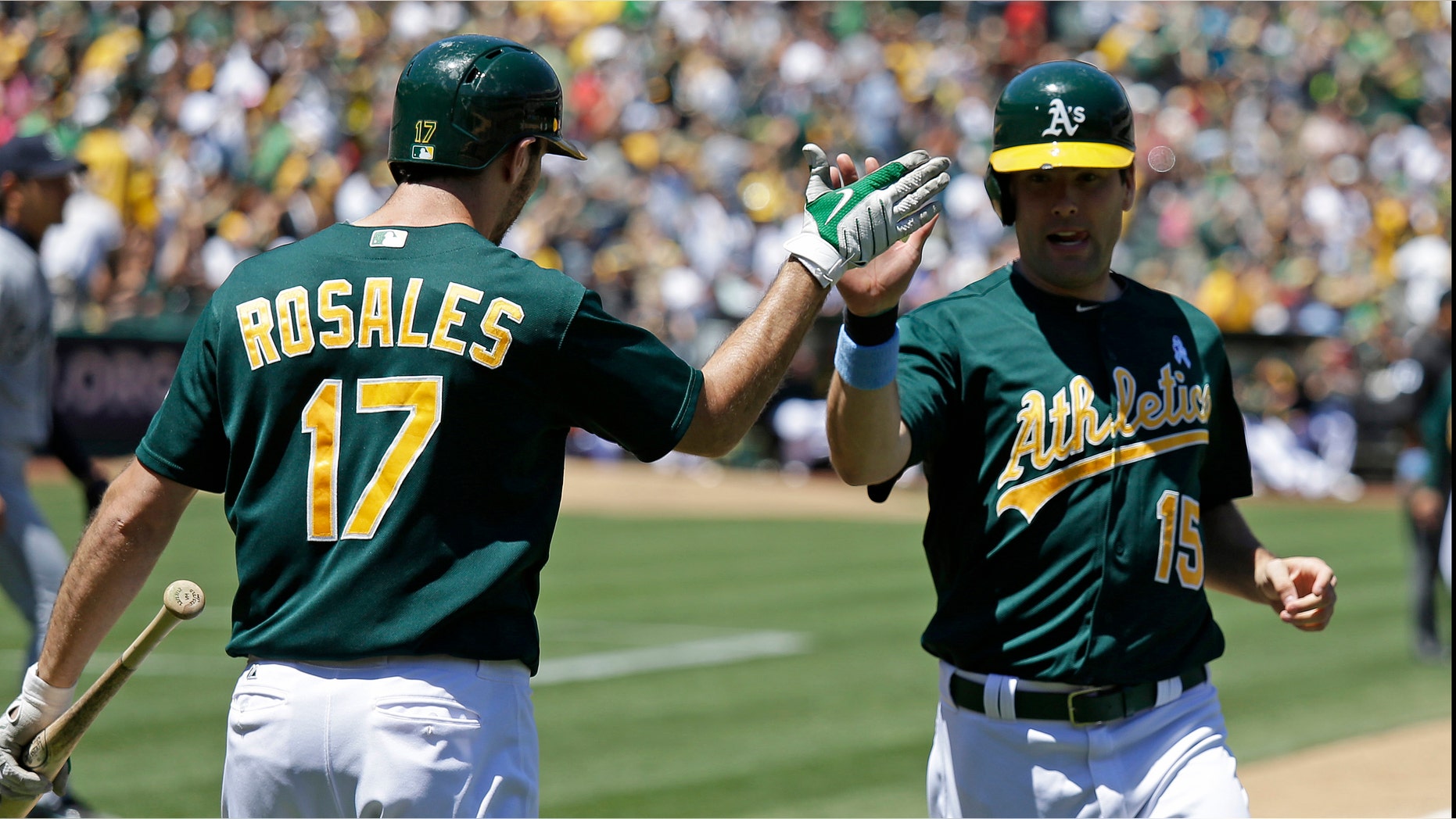Oakland Athletics' Seth Smith, right, is greeted by teammate Adam Rosales, left, after scoring the A's second run in the fourth inning of their baseball game against the Seattle Mariners Sunday, June 16, 2013 in Oakland, Calif. (AP Photo/Eric Risberg)
